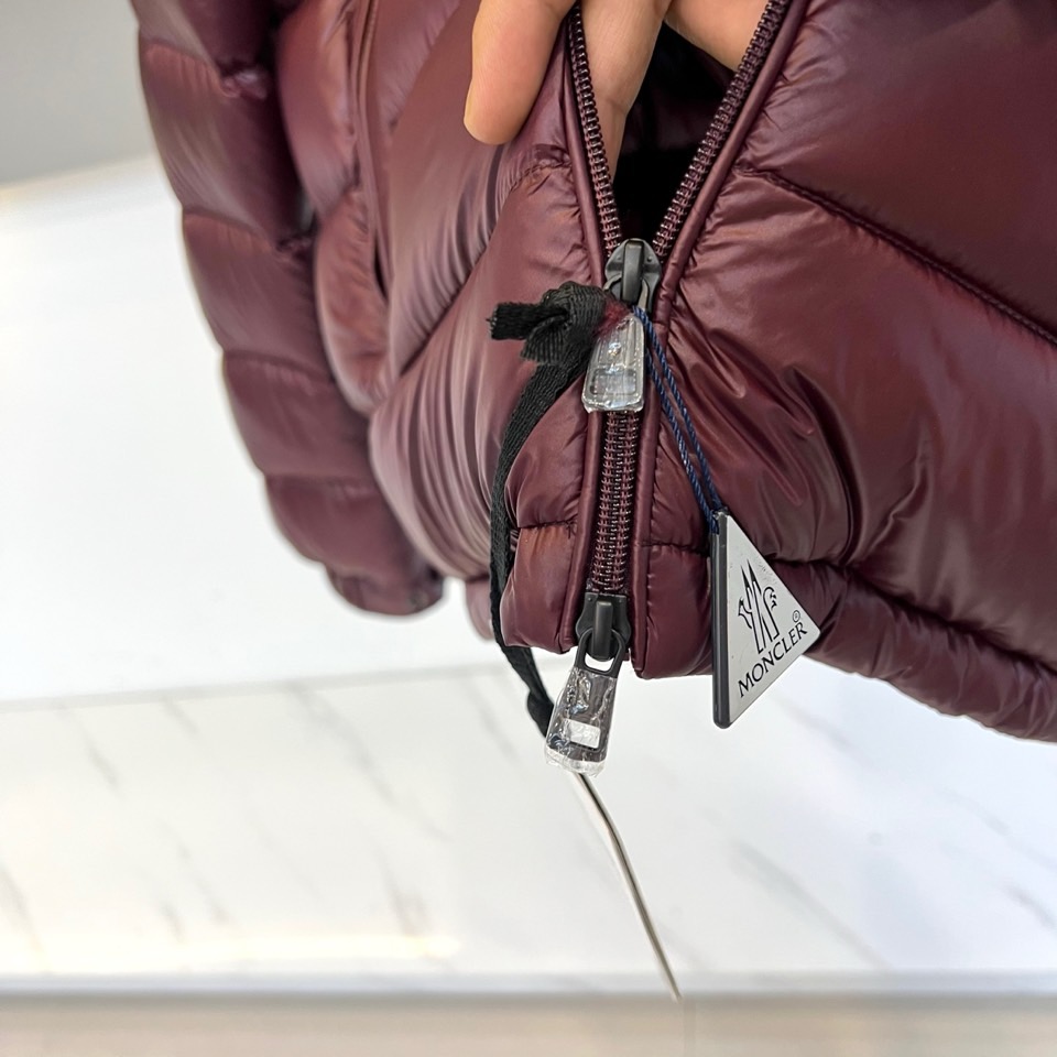 Mon蒙口、2025秋冬新品羽绒服，连帽设计搭配顺滑拉链开合，左臂饰有品牌标志性黑白条纹织带与浮雕徽章，