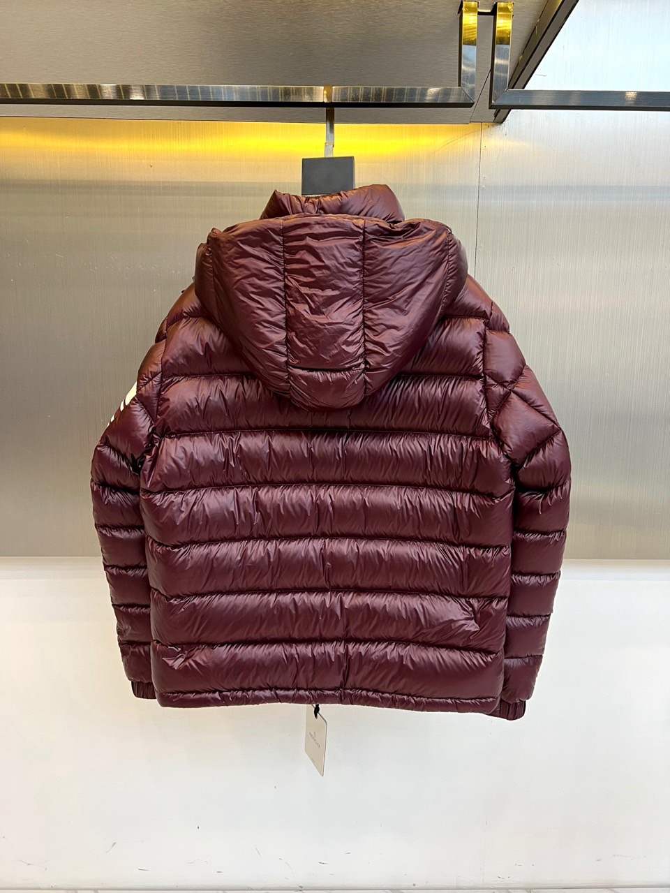 Mon蒙口、2025秋冬新品羽绒服，连帽设计搭配顺滑拉链开合，左臂饰有品牌标志性黑白条纹织带与浮雕徽章，