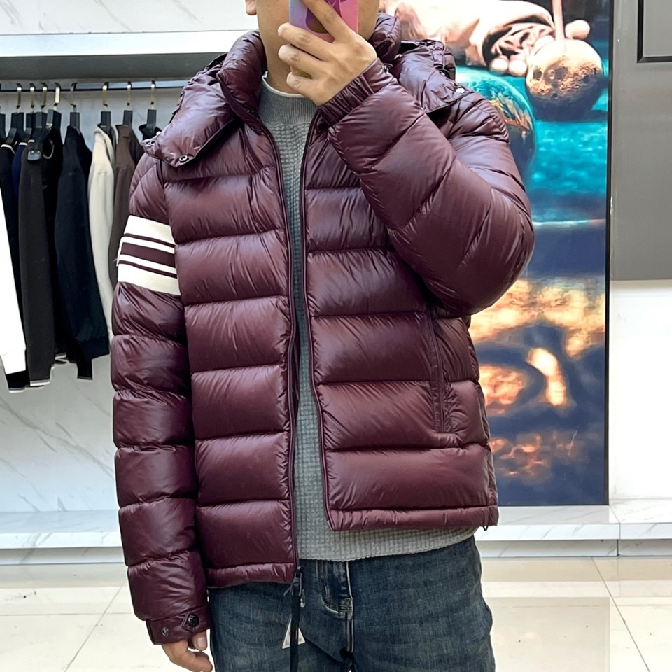 Mon蒙口、2025秋冬新品羽绒服，连帽设计搭配顺滑拉链开合，左臂饰有品牌标志性黑白条纹织带与浮雕徽章，