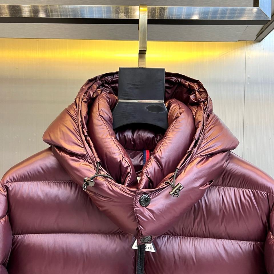 Mon蒙口、2025秋冬新品羽绒服，连帽设计搭配顺滑拉链开合，左臂饰有品牌标志性黑白条纹织带与浮雕徽章，