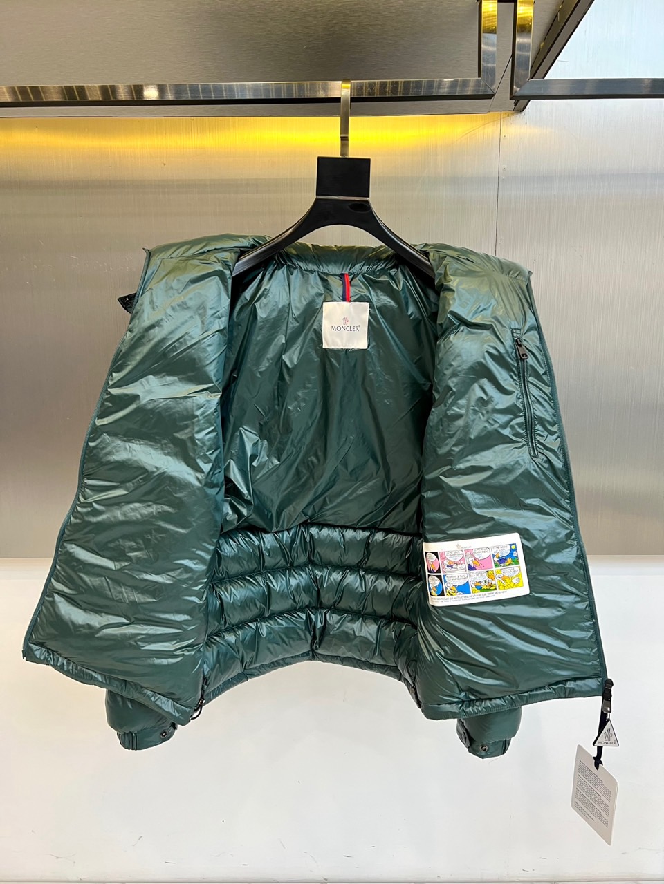 Mon蒙口、2025秋冬新品羽绒服，连帽设计搭配顺滑拉链开合，左臂饰有品牌标志性黑白条纹织带与浮雕徽章，