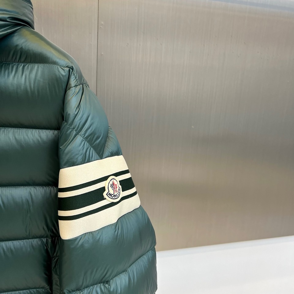 Mon蒙口、2025秋冬新品羽绒服，连帽设计搭配顺滑拉链开合，左臂饰有品牌标志性黑白条纹织带与浮雕徽章，