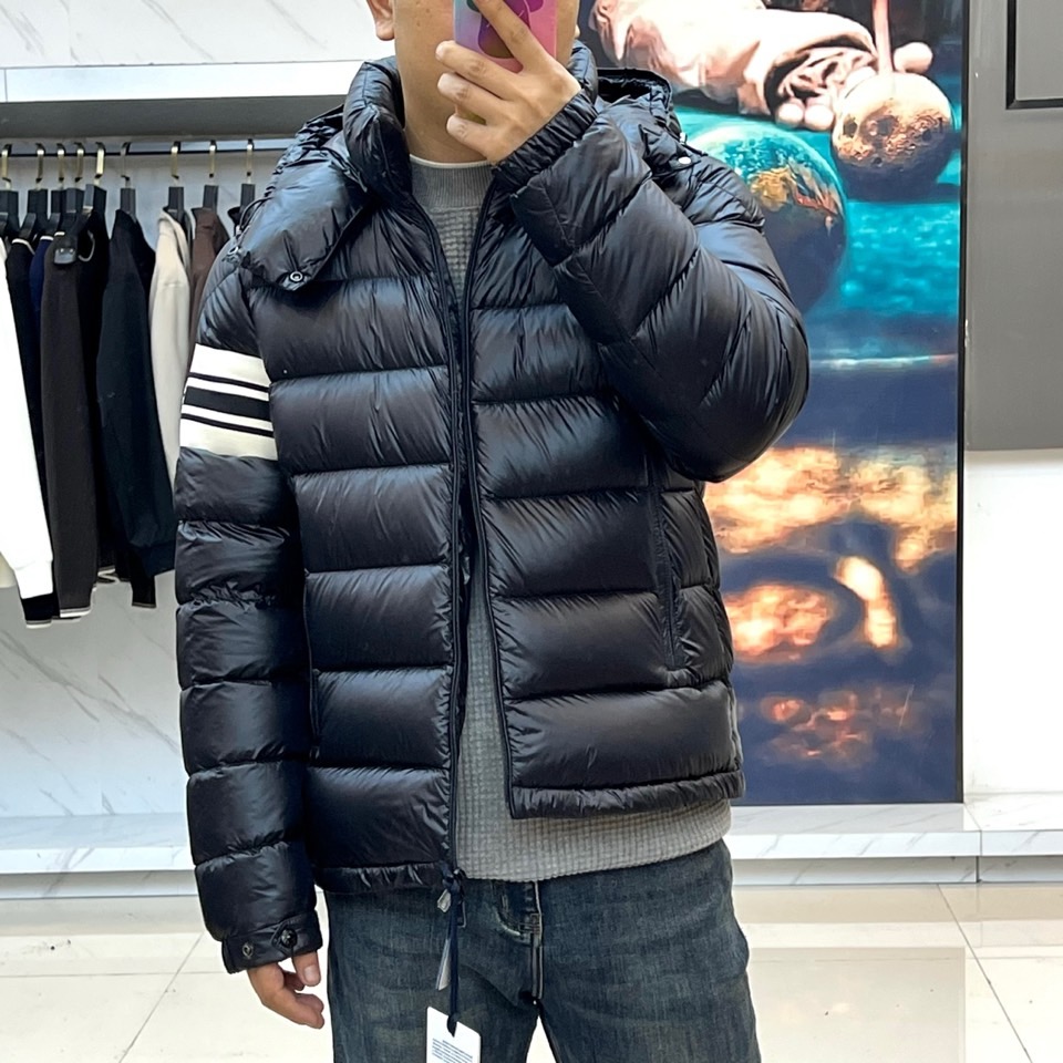 Mon蒙口、2025秋冬新品羽绒服，连帽设计搭配顺滑拉链开合，左臂饰有品牌标志性黑白条纹织带与浮雕徽章，