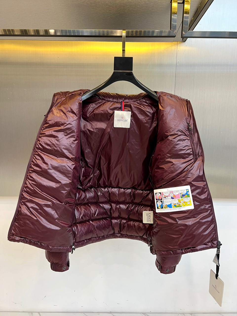 Mon蒙口、2025秋冬新品羽绒服，连帽设计搭配顺滑拉链开合，左臂饰有品牌标志性黑白条纹织带与浮雕徽章，