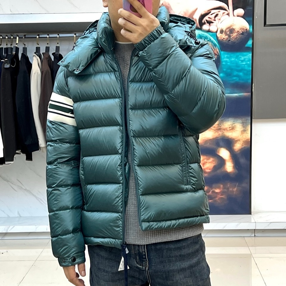 Mon蒙口、2025秋冬新品羽绒服，连帽设计搭配顺滑拉链开合，左臂饰有品牌标志性黑白条纹织带与浮雕徽章，