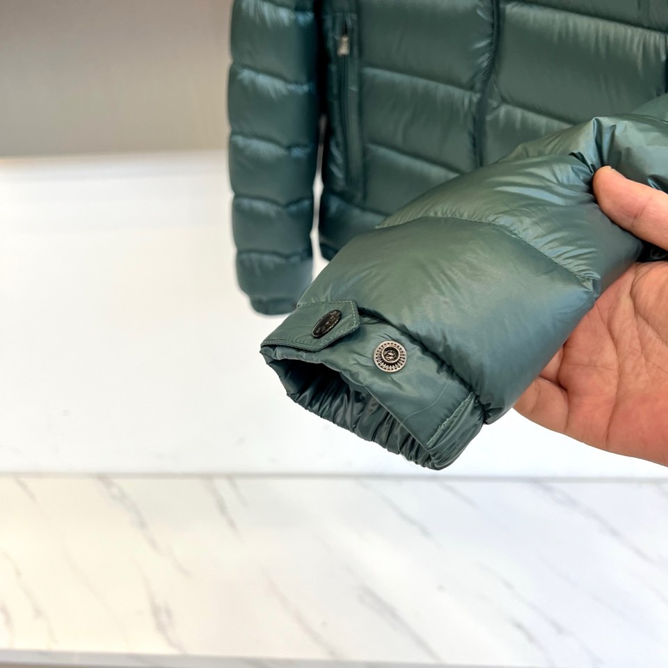 Mon蒙口、2025秋冬新品羽绒服，连帽设计搭配顺滑拉链开合，左臂饰有品牌标志性黑白条纹织带与浮雕徽章，