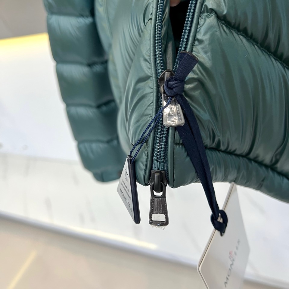 Mon蒙口、2025秋冬新品羽绒服，连帽设计搭配顺滑拉链开合，左臂饰有品牌标志性黑白条纹织带与浮雕徽章，