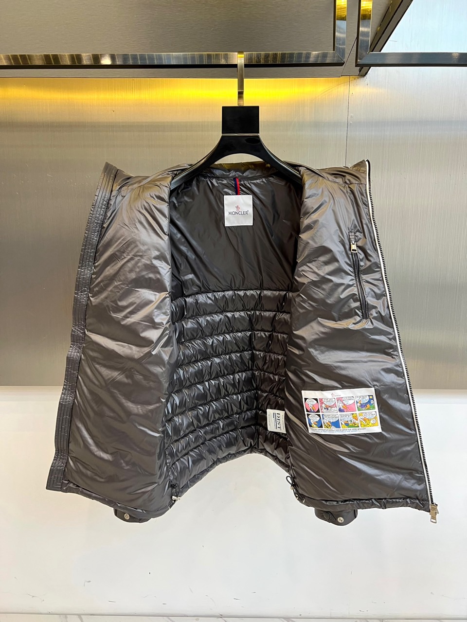 Mon蒙口（纯鹅绒）、2025秋冬新品羽绒服以深灰色调演绎现代极简美学，立领设计搭配银色拉链开合，衣身通