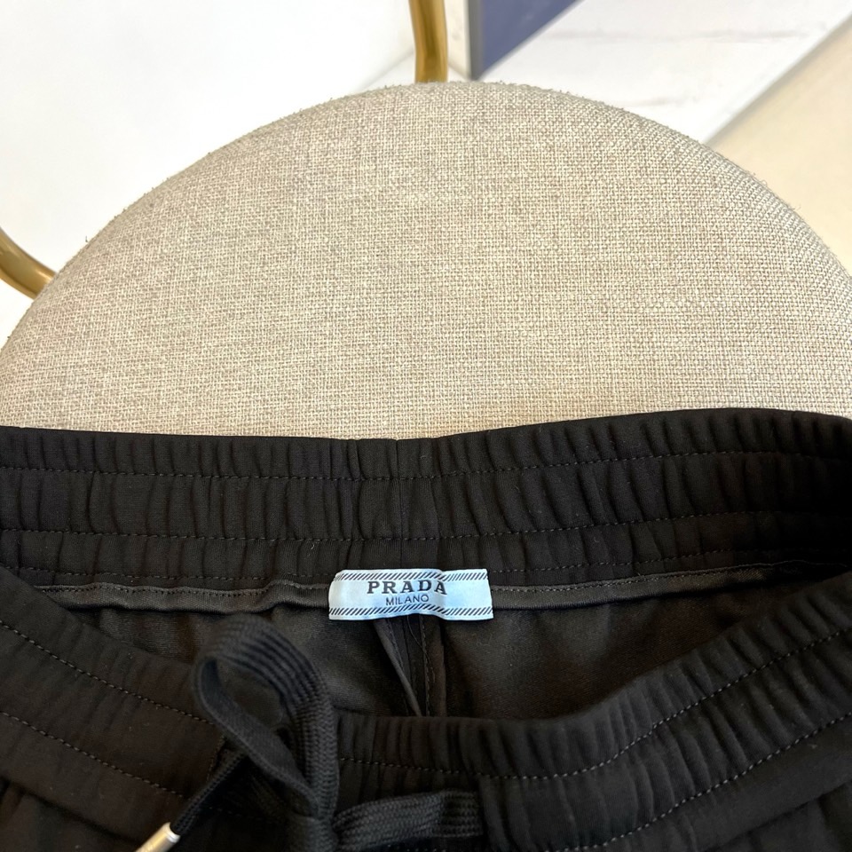 Prad普拉、2025秋冬新品运动长裤，以标志性设计语言诠释现代休闲美学。款式采用弹性抽绳腰头设计，两侧