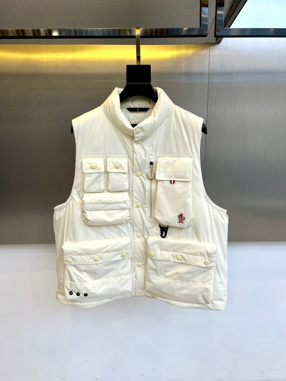 NO:626368,Mon (white goose down), new fall and winter down vest, interprets modern winter style with a minimalist silhouette. The stand-up collar design and single-button closure create clean lines. The pure white tone of the whole body is matched with delicate plaid quilting, highlighting the high-end texture of the fabric.  The essence of this vest lies in its functional aesthetic front, which is cleverly arranged with multiple special-shaped pockets, integrating various closure methods such as snap buttons, zippers and Velcro. The mini logo pocket on the left chest is decorated with red, black and blue details, and the large-capacity three-dimensional pockets on both sides combine practicality and style. Every detail demonstrates the muzzle's balance between function and design.  The inner quality is also excellent. The label information confirms that the fabric and lining are made of nylon, ensuring lightness and wear resistance. The filling is 90 high-quality white goose down, providing a lightweight and top-notch warmth experience. The exquisite craftsmanship made in Romania is reflected in every stitching detail.  This vest is a perfect layering item in autumn and winter. It can be paired with a sweater or shirt, and can easily travel between leisure and business scenes. Through this white down vest, the Mengkou autumn and winter series once again proves that warmth and grace can coexist, providing elegant winter wardrobe solutions for urbanites who pursue quality life. Sizes 1-5 (model 173, 143 pounds, upper body size 2), Moncler, shirts, down jacket, alexander wang19860909Mon蒙口（白鹅绒）、秋冬新品羽绒马甲,以极简轮廓诠释现代冬日型格.立领设计与单颗纽扣开合营造出利落线条,通体纯净的白色调搭配细腻的格纹绗缝,凸显面料的高级质感. 这款马甲的精髓在于其功能性美学前身巧妙布局多个异形口袋,融合按扣、拉链与魔术贴等多种闭合方式.左胸的迷你徽标口袋饰以红黑蓝三色细节点缀,两侧的大容量立体口袋则兼顾实用性与造型感.每一个细节都彰显着蒙口对功能与设计的平衡之道. 内在品质同样卓越.标签信息确认面料与里料均采用锦纶,确保轻盈耐磨.填充物为90高品质白鹅绒,提供轻盈无感的顶级保暖体验.罗马尼亚制造的精致工艺,体现在每一处缝线细节之中. 这款马甲是秋冬叠穿的完美单品,可随意搭配针织衫或衬衫,轻松游走于休闲与商务场景之间.蒙口秋冬系列通过这件白色羽绒马甲,再次证明温暖与风度可以并存,为追求品质生活的都市人士提供冬日衣橱的优雅解决方案.1-5码（模特173,143斤上身2码）,,Moncler,shirts,down jacket,alexander wang,Men's clothing