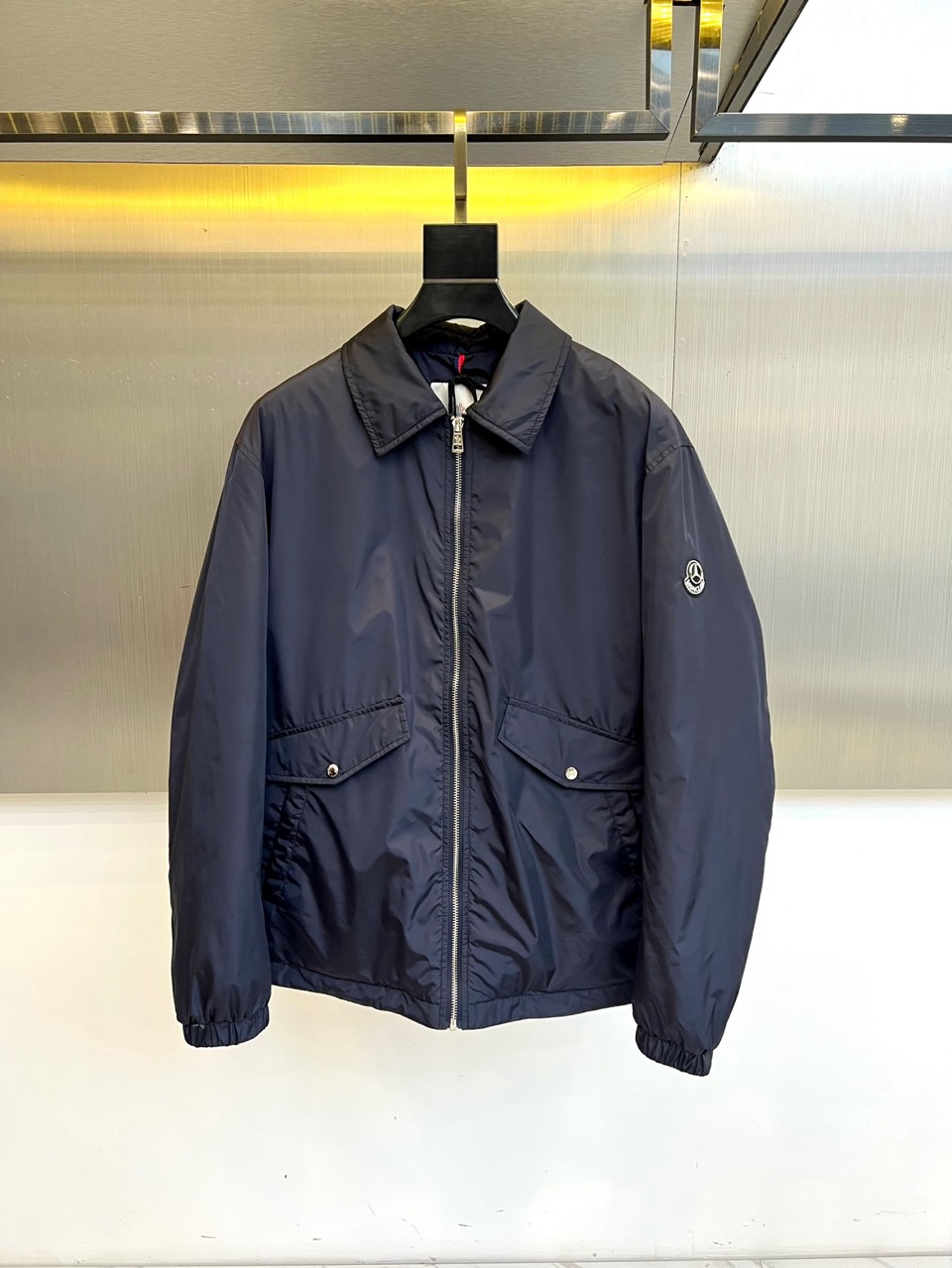 NO:626395,Mon (white goose down), new autumn and winter lightweight down jacket, dark blue jacket interprets practical aesthetics with simple design. The zipper closure is matched with a classic lapel shape, and the brand logo on the left chest low-key highlights the identity. Symmetrical pockets on both sides are equipped with metal snaps, and the cuffs are designed with windproof tightening, taking into account functionality and smooth lines. The fabric is made of nylon and filled with 90 white goose down (decoration)  Except for some parts), it is light, warm, wear-resistant and breathable. The washing label indicates professional wet cleaning care at 30 degrees, and avoid drying and ironing. This jacket is adaptable to many scenes with its neat tailoring. Whether it is urban commuting or leisure travel, it can show a low-key modern style. Sizes 1-5 (model is 173, 143 pounds, upper body size 2), Moncler, jackets  & coats,down jacket,alexander wang19860909Mon蒙口（白鹅绒）、秋冬新品轻薄羽绒夹克,深蓝色夹克以简约设计诠释实用美学.拉链开合搭配经典翻领造型,左胸处的品牌标志低调彰显身份.两侧对称口袋配备金属按扣,袖口采用防风收紧设计,兼顾功能性与流畅线条.面料选用锦纶材质,填充90白鹅绒（装饰部分除外）,轻盈保暖且耐磨透气.水洗标提示30度水温专业湿洗护理,避免烘干熨烫.这款夹克以利落剪裁适应多场景穿搭,无论是都市通勤或休闲出行,皆能展现低调质感的现代风格.1-5码（模特173,143斤上身2码）,,Moncler,jackets & coats,down jacket,alexander wang,Men's clothing