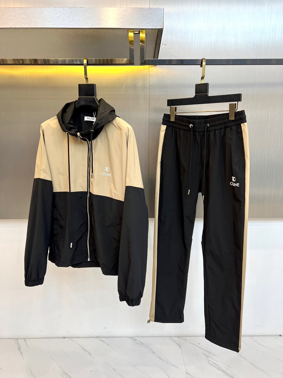 NO:648418,Celine, autumn and winter series of sports suits. Interpret high-end casual style with sports aesthetics. This sports suit consists of a hooded zipper jacket on the top and leggings sweatpants on the bottom. Both are made of ultra-soft modal fabric with delicate touch, giving the skin all-day soft care and freedom.  Dynamic. The jacket is spliced in black and brown to form a three-dimensional and simple visual language. The exquisite brand embroidery on the left chest shows off the identity in a low-key manner. The bottoms are versatile black leggings. The brown stripes inlaid on the sides cleverly echo the color of the top, forming a neat and smooth extension of the lines.  The logo is embellished with details. The tailoring of the suit takes into account both relaxation and slimming, achieving a delicate balance between the dynamic vitality of the hooded jacket and the smart style of the leggings. It seamlessly blends Celine's iconic French simplicity with urban sports style, and the black and brown color combination is calm and advanced, whether it is used for morning training  You can easily control it for training, walking in the city, or creating a fashionable casual travel style. It redefines the modern wardrobe essentials that coexist comfort and style. S-XL (model weighs 173,143 pounds, upper body size M),,celine,celine,jackets  & coats,hats,alexander wang19860909Celine赛琳、秋冬系列运动套装.以运动美学诠释高级休闲风范.本款运动套装由上装连帽拉链外套与下装束脚运动裤组成,均采用触感细腻的超柔莫代尔面料,赋予肌肤全天候的云柔呵护与自由动感.外套以黑、棕双色拼接,构成立体简约的视觉语言,左胸精致的品牌刺绣低调彰显身份.下装为百搭黑色束脚裤型,侧边镶嵌的棕色条纹与上衣配色巧妙呼应,形成利落流畅的线条延伸,裤脚处的标识点缀细节.套装剪裁兼顾松弛感与修身度,在连帽外套的动感活力与束脚裤的干练型格之间达到精妙平衡.它将赛琳标志性的法式简约与都市运动风无缝融合,黑棕配色沉稳高级,无论是用于晨间训练、城市漫步,或是打造时髦的休闲出行造型,皆能轻松驾驭,重新定义舒适与风格并存的现代衣橱必备.S-XL（模特173,143斤上身M码）,,celine,celine,jackets & coats,hats,alexander wang,Men's clothing