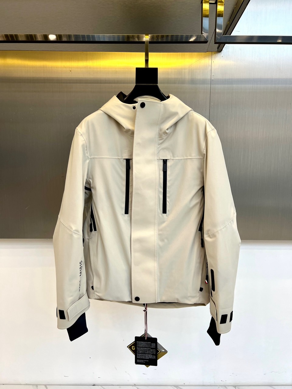 NO:648460,MON's hooded (white velvet), new ski jacket for autumn and winter, uses pure off-white to interpret the minimalist aesthetics of the fusion of mountain and city. The style adopts a professional hood design, with a built-in hood adjustment system, and the stiff brim can effectively block wind and snow. There is a diagonal pocket with a black zipper on the front, which functionally echoes the black buckles and decorative strips at the cuffs, and outlines a neat silhouette in a clear tone. The left sleeve is decorated with a brand logo, highlighting the genes derived from the Alps.  The core technology is equipped with a precision multi-layer structure. The outer layer is a windproof stretch fabric blended with 87 nylon and 13 spandex to ensure freedom of movement. The interior is filled with 90 high-quality white goose down, with a filling capacity of 19 grams, which is light and temperature-locking. The lining system is based on the body  Different parts require differentiated proportions - the main body is made of 85 nylon and 15 spandex to ensure mobility and extensibility, the sleeves and other parts are mainly made of polyester fiber to improve warmth and wear resistance, and the nylon lining at the hem enhances the durability of daily wear.  It seamlessly connects professional ski protective performance with urban minimalist style, and every detail serves dynamic comfort and static style. This ski suit can not only accompany you on the snowy slopes, but its refreshing color matching and smooth tailoring can also be easily integrated into urban daily life, becoming an inseparable connection.  The winter armor in the same scene perfectly interprets MONCLER's design philosophy of integrating ultimate functionality with timeless elegance. Size 0-1-2-3-4 (model weighs 173,143 pounds, upper body size 1),,Moncler,hats,alexander  wang19860909MON蒙口（白鹅绒）、秋冬新品滑雪服,以纯净米白色诠释山野与都市融合的极简美学.款式采用专业连帽设计,内置风帽调节系统,帽檐挺括可有效阻挡风雪.正面设有带黑色拉链的斜插口袋,与袖口处的黑色环扣及装饰条形成功能呼应,在明净色调中勾勒出利落轮廓.左袖饰有品牌标识,彰显源自阿尔卑斯的基因. 核心技术搭载精密多层结构表层为87锦纶与13氨纶混纺的防风弹力面料,确保运动自由度；内里填充90高品质白鹅绒,充绒量19克,轻盈锁温.里料系统根据身体不同部位需求进行差异化配比——主体采用85锦纶与15氨纶保证活动延展性,衣袖等部位以聚酯纤维为主提升保暖与耐磨度,下摆锦纶里料则强化了日常穿着的耐久性. 将专业滑雪防护性能与都市简约风格无缝连接,每一个细节都服务于动态舒适与静态型格.这款滑雪服不仅能陪伴你在雪道上御风驰骋,其清爽配色与流畅剪裁亦能轻松融入都市日常,成为连接不同场景的冬日铠甲,完美诠释MONCLER融合极致功能与永恒优雅的设计哲学.0-1-2-3-4码（模特173,143斤上身1码）,,Moncler,hats,alexander wang,Men's clothing