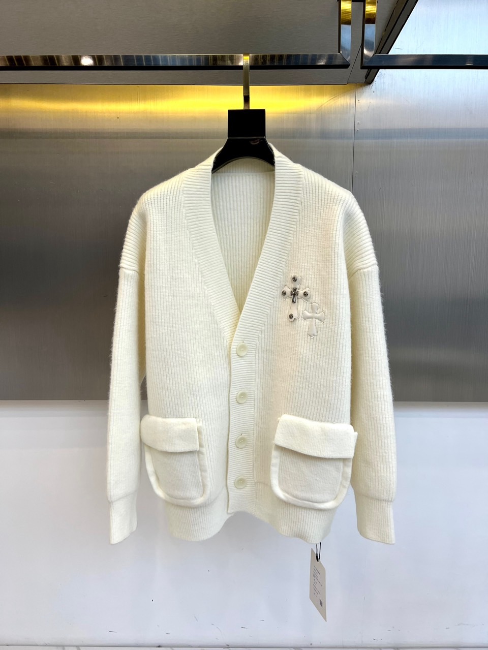 NO:648472,Ch Croix Heart, a new white knitted cardigan for autumn and winter, adopts a classic V-neck design and is equipped with four black round resin buttons, which can be adjusted at will. The left chest is embellished with a delicate cross embroidery pattern and is decorated with small rivets, becoming the iconic visual focus. There are symmetrical practical large pockets on both sides of the body, taking into account functionality and silhouette. The overall fit is loose and comfortable, and the fine knitted texture brings a delicate texture.  The fabric is made of a precise blend of 42 acrylic, 28 nylon and 30 polyester. The acrylic gives a soft wool-like feel and a full and fluffy feel, the nylon enhances the wear resistance and durability of the fabric, and the polyester fiber ensures a stiff shape and is not easily deformed, ensuring a comfortable wearing experience and a long-lasting and stylish silhouette.  Combining the iconic cross rivet elements with everyday practicality, the embroidered details and loose fit become a direct statement of personality. This cardigan can be worn with a T-shirt or shirt to create a layered street look, or can be worn alone to show a simple and cool style. It is suitable for diverse scenes from daily outings to gatherings with friends, and perfectly interprets the brand's design concept of integrating original attitude and trendy practicality. M-L-XL (please state your height and weight when placing an order), chrome hearts, shirts, tees, t-shirts, alexander wang19860909Ch克罗心,秋冬新品白色针织开衫,款式采用经典V领设计,搭配四颗黑色圆形树脂纽扣,可随性调节开合度.左胸点缀精致的十字架刺绣图案,并装饰有小颗铆钉,成为标志性视觉焦点.衣身两侧设有对称的实用大口袋,兼顾功能性与廓形感.整体版型宽松舒适,细密针织纹理带来细腻质感. 面料采用42腈纶、28锦纶与30聚酯纤维的精准混纺,腈纶赋予柔软仿羊毛触感与饱满蓬松感,锦纶增强面料的耐磨性与耐用度,聚酯纤维则保证版型挺括不易变形,确保了舒适的穿着体验与持久有型的轮廓. 将标志性的十字架铆钉元素与日常实穿性相融合,刺绣细节与宽松版型成为个性的直接宣言.这款开衫既能内搭T恤或衬衫打造层次丰富的街头造型,亦可单独穿着展现简约潮酷风格,适合从日常出街到朋友聚会的多元场景,完美诠释品牌融合原创态度与潮流实穿性的设计理念.M-L-XL（下单请报身高体重）,,chrome hearts,shirts,tees，t-shirt,alexander wang,Men's clothing