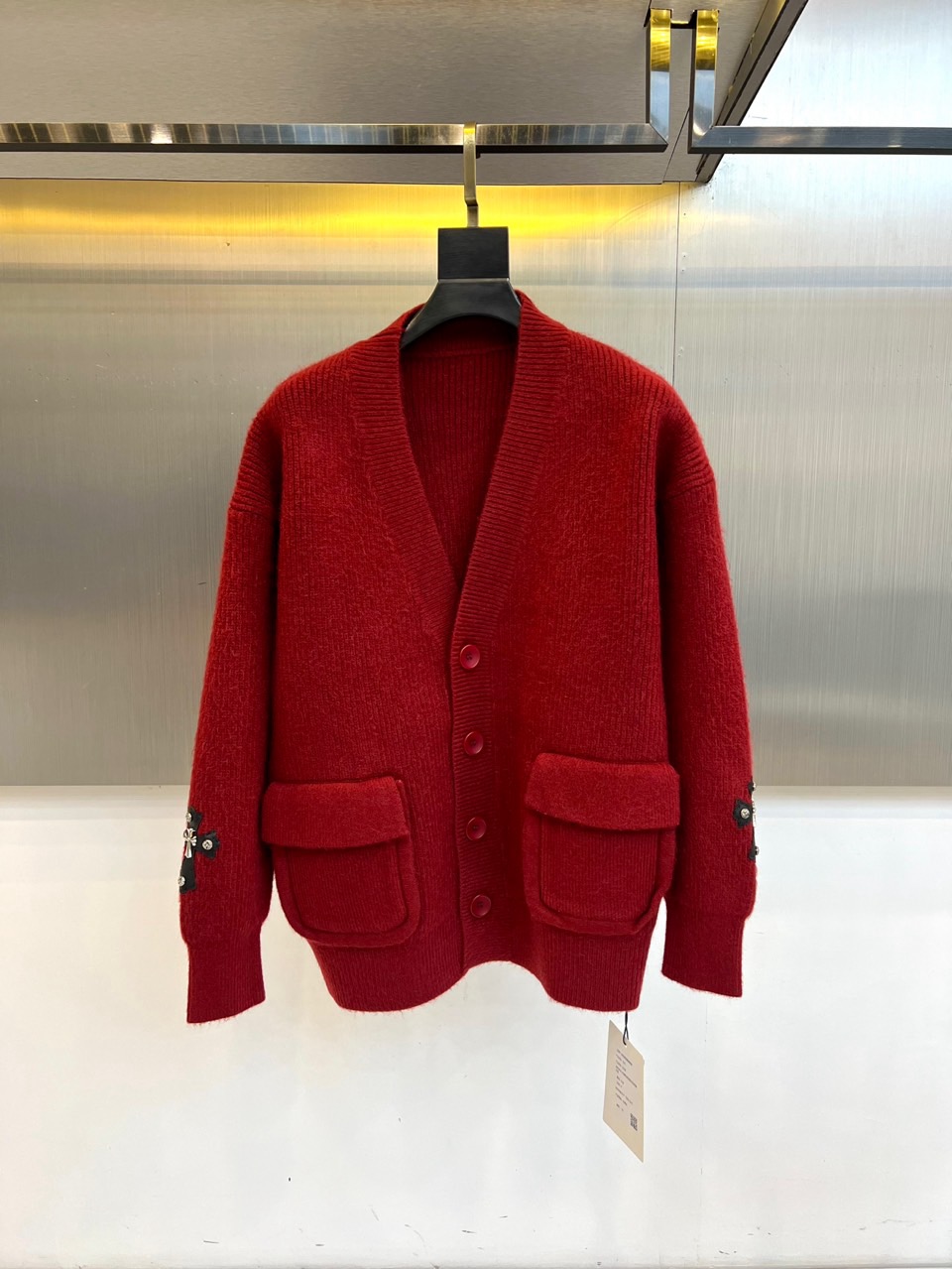 NO:648478,Ch's new red knitted cardigan for autumn and winter interprets the original trendy brand's personalized aesthetics in bright red. The style adopts a classic V-neck design and is equipped with three dark resin buttons, which can be adjusted at will. There are practical large pockets on both sides of the body, taking into account both functionality and relaxed silhouette. The sleeves are decorated with the brand's iconic cross and other badges, using delicate craftsmanship to highlight the uninhibited street gene.  The fabric is made of a precise blend of 42 acrylic, 28 nylon and 30 polyester. The acrylic provides a soft wool-like feel and full fluffiness, the nylon enhances wear-resistance and toughness, and the polyester fiber ensures a stiff silhouette that is not easily deformed. The overall silhouette is loose and casual, with a soft and comfortable touch.  Combining street spirit with daily practicality, badge decoration and eye-catching red become a direct statement of personality. This cardigan can be worn with a basic T-shirt to create a layered street look, or can be worn alone to show a striking style. It is suitable for various occasions from daily travel to casual gatherings, and perfectly interprets the design concept of combining original attitude and trendy practicality. S-XL (model 173, 143 pounds, upper body size M),, chrome hearts, tees, t-shirt, alexander wang19860909Ch克罗心、秋冬新品红色针织开衫,以鲜明亮眼的红色诠释原创潮牌的个性美学.款式采用经典V领设计,搭配三颗深色树脂纽扣,可随性调节开合度.衣身两侧设有实用大口袋,兼顾功能性与松弛轮廓.袖管饰有品牌标志性的十字架等徽章装饰,以细腻工艺彰显不羁的街头基因. 面料选用42腈纶、28锦纶与30聚酯纤维的精准混纺,腈纶提供柔软的仿羊毛触感与饱满蓬松度,锦纶增强耐磨韧性,聚酯纤维保证版型挺括不易变形.整体版型宽松休闲,触感柔软舒适. 将街头精神与日常实穿性相融合,徽章装饰与醒目红色成为个性的直接宣言.这款开衫既能内搭基础款T恤打造层次感街头造型,亦可单独穿着展现醒目型格,适合从日常出行到休闲聚会的多种场合,完美诠释融合原创态度与潮流实穿性的设计理念.S-XL（模特173,143斤上身M码）,,chrome hearts,tees，t-shirt,alexander wang,Men's clothing