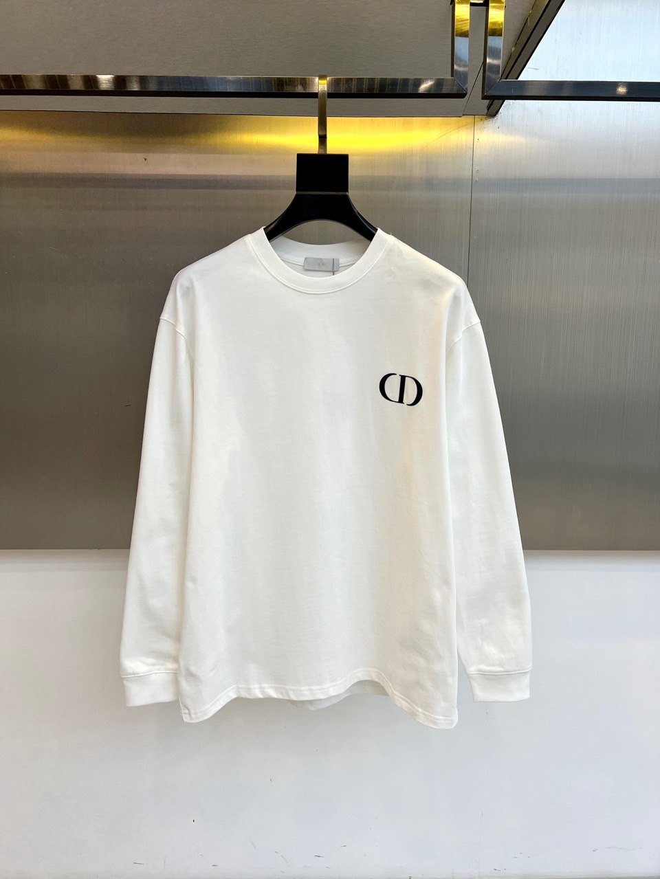 NO:650764,Dio, Dior's new 2025 autumn and winter long-sleeved T-shirt interprets timeless French elegance with a minimalist design. The style adopts a comfortable round neck and a moderately loose fit to ensure free movement and body shape. The iconic black 'CD' logo is embellished on the chest, and the precise embroidery process presents a clear and three-dimensional brand imprint. The fabric is made of combed cotton, which is soft in texture and has good breathability and durability.  The style perfectly balances luxury genes and daily practicality. The pure white color is used as a versatile base. It can be worn alone with jeans to show casual charm, or it can be worn as an inner layer with a suit or a windbreaker to create a layered look. The black logo and the white base fabric form a classic contrast, inadvertently revealing a low-key luxury attitude. This T-shirt is carefully selected through fabric selection  Selected and precisely tailored, it has become an indispensable universal item in the autumn and winter wardrobe. It can demonstrate Dior's unique exquisite aesthetics whether it is daily commuting or casual social occasions. S-XXL (model weighs 173,143 pounds, upper body size M),, dior, dior, jeans, tees, t-shirt, business  suit,alexander wang19860909Dio迪奥、2025秋冬新品长袖T恤以极简设计诠释永恒的法式优雅.款式采用舒适圆领与适度宽松的版型,确保活动自如且不挑身形.胸前点缀标志性黑色'CD'徽标,以精工刺绣工艺呈现清晰立体的品牌印记.面料选用精梳棉,质地柔软且具备良好的透气性与耐久度. 风格上完美平衡奢华基因与日常实穿性,纯净白色调作为百搭基底,既能单穿搭配牛仔裤展现休闲魅力,亦可作为内搭与西装、风衣叠穿塑造层次感造型.黑色徽标与白色底布形成经典对比,在不经意间流露低调的奢华态度.这件T恤通过考究的面料选择与精准剪裁,成为秋冬衣橱中不可或缺的万能单品,无论日常通勤或休闲社交场合皆能彰显迪奥独有的精致美学.S-XXL（模特173,143斤上身M码）,,dior,dior,jeans,tees，t-shirt,business suit,alexander wang,Men's clothing