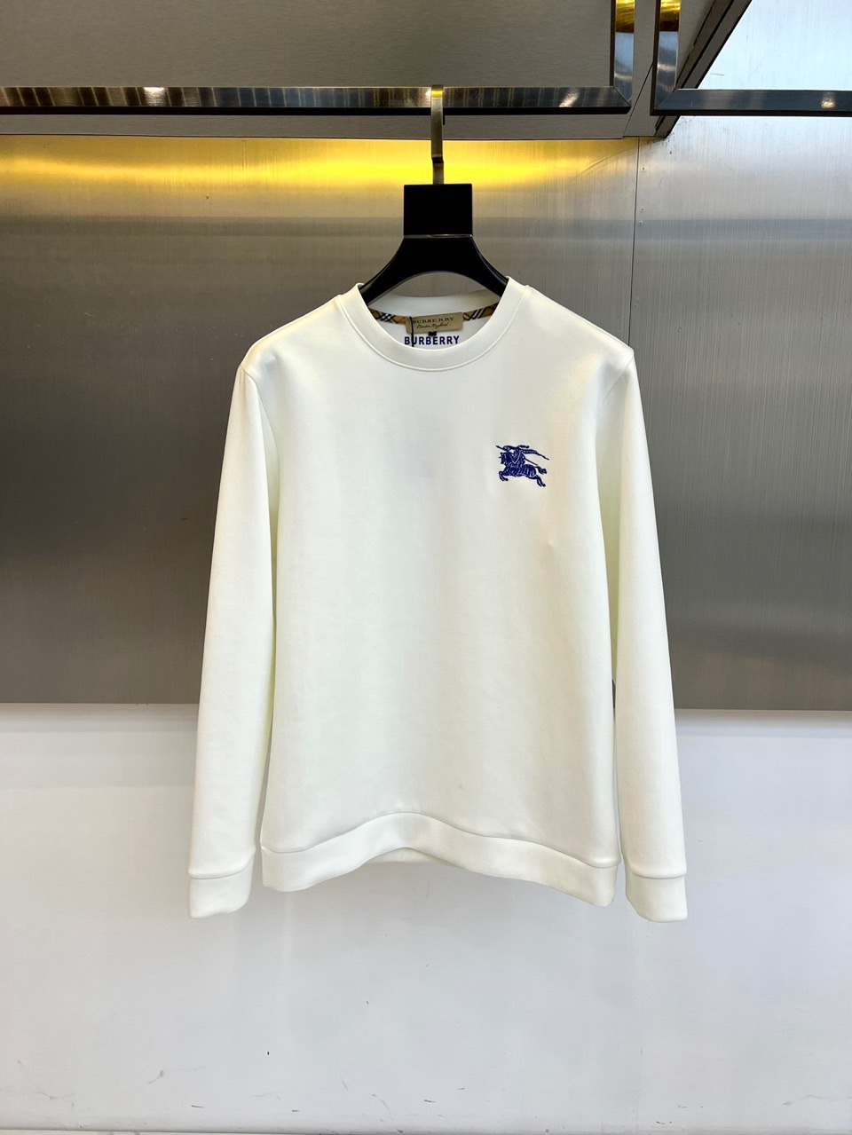 NO:650771,Burberry, 2025 autumn and winter new men's air-layer sweatshirt. This round-neck sweatshirt is made of air-layer fabric. The precise ratio of 95% cotton and 5% spandex ensures that the clothing is soft and skin-friendly and moderately elastic. The left chest is embellished with the brand's iconic blue knight embroidery badge, using three-dimensional stitching to outline the century-old brand genes. The inside of the collar is decorated with a classic plaid lining, hiding the BURBERRY brand logo, revealing a luxurious texture in the details.  The sweatshirt adopts three-dimensional cutting technology, and the shoulder line is ergonomically calculated to ensure freedom of movement. The cuffs and hem are designed with high-density ribbing. The fabric uses an air layer weaving method to form a warm air layer, which is suitable for wearing alone or as an inner layer. It complies with international washing standards and supports warm water machine washing and low temperature drying for easy daily care.  Its design perfectly combines street casualness with British elegance. The pure white color scheme highlights the minimalist style, and the slim but not tight version is suitable for a variety of wearing scenarios. Whether it is paired with casual trousers to create a daily look, or layered under a jacket, it can naturally show a low-key fashion attitude. From urban strolls to weekend trips, this sweatshirt  With its excellent comfort and exquisite brand details, it has become a must-have item in the autumn and winter wardrobes of those who pursue quality life. M-4XL (model weighs 173,143 pounds, upper body size L),,burberry,burberry,hoodie,sweatshirts,jackets  & coats,alexander wang19860909Bur巴宝莉、2025秋冬新品男士空气层卫衣,这款圆领卫衣采用空气层面料打造,95棉与5氨纶的精准配比确保衣物兼具柔软亲肤感与适度弹性.左胸处点缀品牌标志性蓝色骑士刺绣徽章,以立体针法勾勒百年品牌基因.衣领内侧饰有经典格纹内衬,暗藏BURBERRY品牌标识,于细节处流露奢华质感. 卫衣采用立体剪裁工艺,肩线经过人体工学计算确保活动自由度,袖口与下摆采用高密度罗纹收口设计.面料通过空气层织法形成保暖空气层,既适合单穿也可作为内搭.符合国际洗涤标准,支持温水机洗与低温烘干,便于日常打理. 其设计将街头休闲与英伦优雅完美融合,纯白配色彰显极简风尚,修身而不紧绷的版型适配多种穿搭场景.无论是搭配休闲长裤打造日常造型,还是在外套内展现层次穿搭,都能自然展现低调的时尚态度.从都市漫步到周末出行,这件卫衣以其卓越的舒适度与精致的品牌细节,成为追求品质生活人士秋冬衣橱中的必备单品.M-4XL（模特173,143斤上身L码）,,burberry,burberry,hoodie,sweatshirts,jackets & coats,alexander wang,Men's clothing