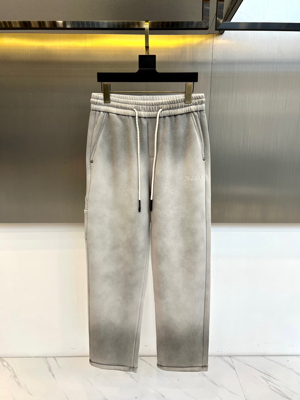 NO:650799,Prad, the new casual pants for autumn and winter 2025, interpret modern casual style in light gray tones. These pants are designed with a drawstring waistband to easily adjust the tightness to ensure a personalized fit and comfortable experience. Practical pockets on both sides combine storage functions and smooth lines, and the brand's iconic 'PRADA' logo is embellished on one side of the pants, low-key highlighting luxury genes. Its design perfectly combines simple aesthetics and pragmatism, with a straight cut to fit a variety of body shapes, and the light gray tone gives the shape a fresh atmosphere  . In terms of style, these casual pants interpret daily elegance with a casual attitude. Whether paired with a simple top to create a casual look, or layered with a jacket to create a layered look, it can easily cope with various occasions. From outings in the city to weekend parties, it uses Prada's consistent exquisite craftsmanship and low-key luxury, becoming a must-have item in the autumn and winter wardrobe that is both practical and fashionable. 48-56 (model is 173, 143 pounds, upper body size 50),, prada, prada, jackets  & coats,alexander wang19860909Prad普拉达、2025秋冬新品休闲裤以浅灰色调演绎现代休闲风尚.这款裤子采用抽绳腰头设计,方便调节松紧度,确保个性化贴合与舒适体验.两侧实用口袋兼顾储物功能与流畅线条,裤身一侧点缀品牌标志性'PRADA'标识,低调彰显奢华基因.其设计将简约美学与实用主义完美融合,直筒剪裁适配多种身形,浅灰色调赋予造型清新气息.风格上,这款休闲裤以随性态度诠释日常优雅,无论是搭配简约上衣打造休闲造型,还是层叠外套展现层次感,都能轻松应对多种场合.从城市出街到周末聚会,它都以普拉达一贯的精湛工艺与低调奢华,成为秋冬衣橱中兼具实穿性与时尚感的必备单品.48-56（模特173,143斤上身50码）,,prada,prada,jackets & coats,alexander wang,Men's clothing