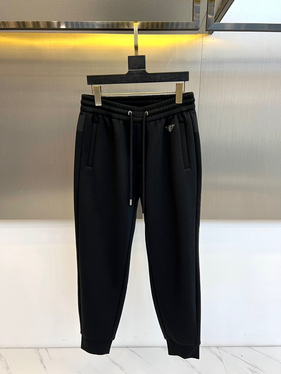 NO:650748,Prad, 2025 autumn and winter new product P home velvet thickened casual sweatpants, velvet sports trousers with both luxurious texture and practical comfort.  The trousers are in a classic black tone with clean and smooth lines. The high-waisted elastic band design and built-in drawstring ensure a secure fit. The ends of the drawstring are embellished with metal heads to highlight the craftsmanship of the details. The iconic triangular metal logo is exquisitely inlaid on the right side of the waistband, low-key confirming the brand identity. The trouser legs are cut with fashionable ankles and are equipped with practical slant pockets on both sides, which perfectly balances sports function and modern silhouette.  Its core lies in an excellent wearing experience. The delicate velvet material inside provides a light and soft skin-friendly touch and continuous warmth, specially designed for the cold climate of autumn and winter. The outer fabric has a smooth and crisp texture, combined with precise stitching technology to ensure durability and a high-end look and feel.  The overall style perfectly combines the luxurious genes of Italian simplicity and the free and easy energy of urban sports style. It can be paired with sweatshirts from the same series to create an all-black modern look, or it can be combined with casual jackets or simple coats, easily transitioning to a variety of casual and semi-formal occasions, becoming an indispensable luxury basic item in the autumn and winter wardrobe. M-4XL (model 173,143 pounds upper body size L),, prada, prada, hoodie, sweatshirts, jackets & coats, alexander wang19860909Prad普拉、2025秋冬新品P家加绒加厚休闲卫裤,兼具奢华质感与实用舒适的加绒运动长裤. 裤子采用经典黑色调,线条利落流畅.高腰松紧带设计结合内置抽绳,确保贴合稳固；抽绳两端点缀金属饰头,彰显细节匠心.标志性的三角形金属徽标精致镶嵌于裤腰右侧,低调印证品牌身份.裤腿采用时髦的束脚剪裁,两侧配备实用的斜插口袋,完美平衡运动功能与现代廓形. 其核心在于卓越的穿着体验内里细腻的加绒材质,提供轻盈柔软的亲肤触感与持续温暖,专为秋冬寒冷气候考量.外部面料质感顺滑挺括,结合精准缝线工艺,确保耐久性与高级观感. 整体风格完美融合了意式简约的奢华基因与都市运动风的洒脱活力.它既能搭配同系列卫衣打造全黑摩登造型,亦可与休闲外套或简约大衣组合,轻松过渡于多种休闲及半正式场合,成为秋冬衣橱中不可或缺的奢华基础单品.M-4XL（模特173,143斤上身L码）,,prada,prada,hoodie,sweatshirts,jackets & coats,alexander wang,Men's clothing