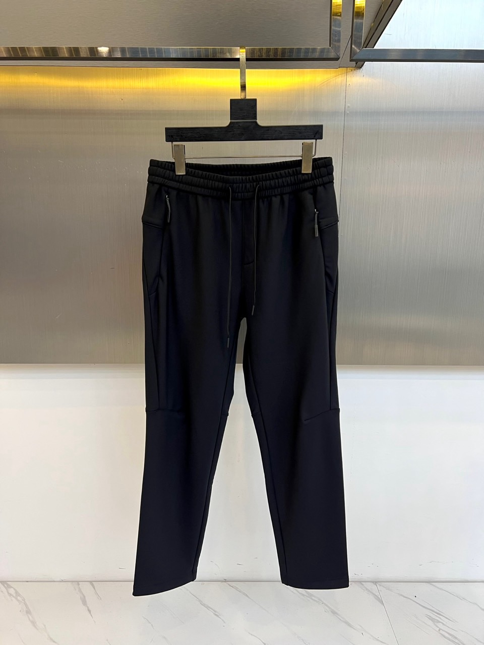 NO:650773,DESCENTE, 2025 autumn and winter new black casual pants and matching down jacket details, interpret urban sports aesthetics with an all-black look.  This leggings trousers are cut in a three-dimensional slim fit, and the waist is designed with elastic elastic bands and adjustable drawstrings to ensure a snug fit without restraint. There is a three-dimensional zippered pocket on each thigh on both sides, which not only enhances the practical storage function, but also injects neat functional lines into the simple silhouette. The trouser legs are neatly gathered in, and the fabric has a soft and drapey texture, taking into account both dynamic comfort and static style.  The details of the down jacket that echoes the same show the brand's meticulous research on materials. The outer side is made of fine and soft fluffy texture fabric, which is rich to the touch and has excellent warmth retention properties; the inner side is made of flat and tight black fabric, and the two are firmly combined through precise stitching technology, reflecting the different functional considerations and detailed ingenuity of the inside and outside.  The overall style deeply integrates sports function and urban simplicity. Whether worn alone or in combination, it can easily cope with diverse scenes from daily commuting, casual socializing to light sports. With this series, Descente interprets the brand's consistently high standards - while pursuing fashionable form, it never compromises on wearing experience and practical functions, providing smart winter wardrobe solutions for modern consumers who pursue quality and style. 32-38 (no 37),, down jacket, alexander wang19860909DESCENTE迪桑特、2025秋冬新品黑色休闲束脚裤与配套羽绒服细节,以全黑造型演绎都市运动美学. 该款束脚裤采用立体修身剪裁,腰部设计为弹力松紧带搭配可调节抽绳,确保穿着贴合且无束缚.两侧大腿处各设有一个带拉链的立体口袋,在提升实用储物功能的同时,为简约轮廓注入利落的机能线条.裤腿收束设计利落,面料呈现柔软垂坠的质感,兼顾动态舒适度与静态型格. 与之呼应的羽绒服细节,则展现了品牌对材质的精研外侧采用细腻柔软的绒毛质感面料,触感丰盈且具备出色的保暖性能；内侧则选用平整紧密的黑色布料,通过精密的缝线工艺将二者稳固结合,体现了内外有别的功能考量与细节匠心. 整体风格将运动机能与都市简约深度融合,无论是单独搭配还是组合穿着,都能轻松应对从日常通勤、休闲社交到轻度运动的多元场景.迪桑特以此系列诠释了品牌一贯的高标准——在追求时尚形态的同时,绝不妥协于穿着体验与实用功能,为追求品质与型格的现代消费者提供冬日衣橱的智慧解决方案.32-38（无37）,,down jacket,alexander wang,Men's clothing