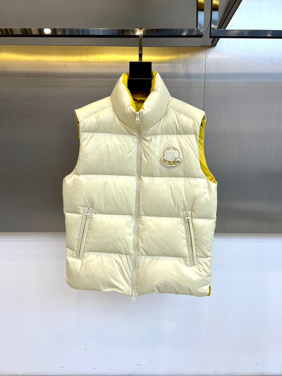 NO:650781,MON's new down vest for the fall and winter of 2025 features a stand-up collar design to enhance neck warmth and neat styling. It is equipped with a smooth zipper closure on the front and zippered hand pockets on both sides, taking into account practical security and smooth lines. The left chest is embellished with the iconic embroidered badge to highlight the brand's genes. The interior is lined with bright yellow, which inadvertently reveals fashionable ingenuity when wearing it.  The fabric is made of nylon, which is lightweight, wear-resistant and windproof. The filling is 90% down and 10% feather, which provides excellent warmth retention in a light and fluffy texture. The overall tailoring focuses on the balance between moderate fluffiness and slim silhouette. It can be worn alone to create a simple layer, or layered under a jacket to enhance cold protection.  The label indicates detailed maintenance guidelines. It is recommended to wash separately at 30℃ water temperature, do not bleach with chlorine, and do not iron directly (a pad is required). It is recommended to wash and iron inside out to better maintain the condition of the fabric and filling. This down vest comes from 'STERLING  1961-1986' series design inspiration combines the outdoor spirit of the Alps with urban simplicity. The bright yellow lining and exquisite badges become a low-key fashion statement. It is not only a practical choice to cope with the temperature difference between autumn and winter, but also a fashion item that can easily create layered shapes. It perfectly interprets MONCLER's design philosophy of integrating professional protection and modern aesthetics. 1-5 (model 173,143 pounds upper body size 2),, Moncler, jackets & coats, jacket, alexander wangdown19860909MON蒙口、 2025秋冬新品羽绒马甲,款式采用立领设计,提升颈部保暖性与利落造型感.正面配备顺滑拉链开合,两侧设带拉链的插手口袋,兼顾实用安全感与流畅线条.左胸点缀标志性刺绣徽章,彰显品牌基因.内里运用亮眼黄色衬里,在穿着时不经意间流露时尚巧思. 面料选用尼龙材质,轻量耐磨并具备防风性能.填充物为90羽绒与10羽毛,在轻盈蓬松的质感中提供出色保暖效果.整体剪裁注重适度蓬松感与修身轮廓的平衡,既能单独穿着打造简约层次,也可内搭于外套之中增强御寒性能. 标签注明细致的养护指南建议30℃水温单独洗涤、不可氯漂、不可直接熨烫（需使用垫布）,推荐翻面洗涤与熨烫以更好维持面料与填充物状态.这款羽绒马甲源自“STERLING 1961-1986”系列设计灵感,将阿尔卑斯户外精神与都市简约风格相融合,亮黄内里与精致徽章成为低调的时尚宣言.它不仅是应对秋冬温差的实用之选,更是轻松打造层次造型的时尚单品,完美诠释MONCLER融合专业防护与现代美学的设计哲学.1-5（模特173,143斤上身2码）,,Moncler,jackets & coats,down jacket,alexander wang,Men's clothing