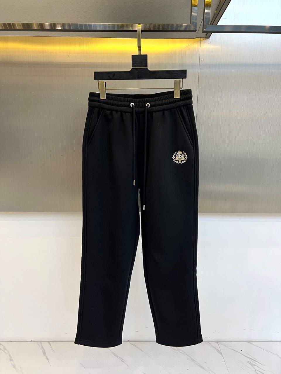NO:656047,Burberry, 2025 autumn and winter series velvet thickened straight casual sweatpants. These men's casual trousers are made of high-quality thickened fabrics, with a luxurious and soft dark red thermal velvet lining inside, which locks in warmth and feels skin-friendly. The elastic drawstring design at the waist ensures a comfortable fit when worn, and practical pockets on both sides combine function and simple outline. The iconic white embroidered badge on the left trouser leg low-key proves the classic British heritage. The elastic cuff design at the trouser legs,  It is effectively windproof and neat and stylish. It perfectly combines Burberry's classic style with practical warmth performance. It contains ingenious details under the simple black appearance. Whether it is daily commuting in the city or leisure weekend travel, it can provide warm protection and calm style, redefining the must-have item in autumn and winter. M-4XL (model 173, 143 pounds, upper body size L),, burberry, burberry, alexander  wang19860909Bur巴宝莉、2025秋冬系列加绒加厚直筒休闲活动卫裤.这款男士休闲长裤选用高品质加厚面料,内部搭载奢华柔软的深红色热绒内里,锁住温暖,触感亲肤.腰部松紧抽绳设计确保穿着时的自如贴合,两侧实用口袋兼顾功能与简洁轮廓.标志性的左裤腿白色刺绣徽章,低调印证经典英伦血脉.裤脚处的弹性收口设计,有效防风且利落有型.它将巴宝莉的经典格调与实用保暖性能完美融合,在简约的黑色外表下蕴藏匠心细节,无论是都市日常通勤,或是闲暇周末出行,皆能提供温暖守护与从容型格,重新定义秋冬季节的必备单品.M-4XL（模特173,143斤上身L码）,,burberry,burberry,alexander wang,Men's clothing