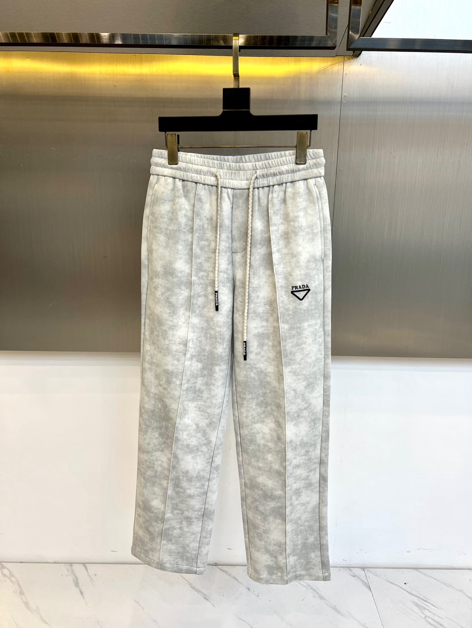 NO:656052,Prada, the new casual pants for autumn and winter 2025, use light gray tones and unique smudged textures to interpret a low-key and high-end feel. The classic wide-leg version has smooth lines, and the draped fabric creates a natural movement. The drawstring waist design cleverly combines comfort and casual style. The iconic triangle logo on the upper left leg has become a symbol of simple design.  The finishing touch. The whole perfectly combines Italian craftsmanship with modern casual aesthetics, combining the comfort of home with the sophistication required for going out, easily creating an effortlessly fashionable autumn and winter look. 48-56 (model 173,143 pounds, upper body size 50),, prada, prada, alexander  wang19860909Prad普拉达、2025秋冬新品休闲裤,以浅灰色调与独特晕染纹理诠释低调高级感.经典阔腿版型线条流畅,垂坠面料营造自然动感.抽绳腰头设计巧妙融合舒适体验与随性风格.左腿上方标志性三角徽标,成为简约设计的了点睛之笔.整体将意式工艺与现代休闲美学完美结合,兼具居家般的自在与外出所需的精致,轻松打造不费力的时髦秋冬造型.48-56（模特173,143斤上身50码）,,prada,prada,alexander wang,Men's clothing