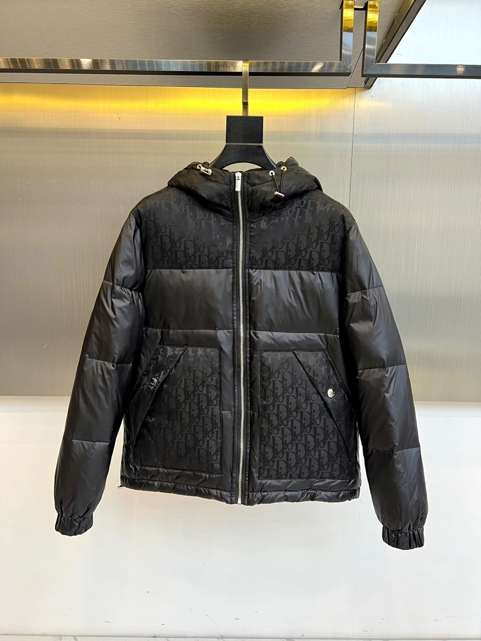NO:656079,Dio Dior, the new 2025 autumn and winter down jacket, uses classic black to interpret timeless elegance. The slim cut accurately fits the body line, and the neat shoulder line and hooded design cleverly balance urban modernity and practical functions. The brand's iconic presbyopia pattern is spread all over the body, low-key showing the extraordinary identity through exquisite jacquard technology, and perfectly integrating retro genes and modern aesthetics. The diagonal pockets on both sides are decorated with metal snaps, which enhances the overall sophistication in details.  This product is made of high-density windproof fabric and filled with high-quality down to ensure excellent thermal insulation performance with a light body feel. Details such as smooth zipper opening and windproof cuffs further reflect the thoughtful consideration of practicality. The overall design condenses the exquisite craftsmanship of the Dior Haute Couture House into an everyday jacket, no matter what  Whether paired with formal trousers for formal occasions, or combined with simple casual attire, it can be the finishing touch of autumn and winter looks, showing luxury connotation and extraordinary taste in a low-key manner. 48-56 (model weighs 173,143 pounds, upper body size 50),, dior, dior, jackets  & coats,down jacket,hats,alexander wang19860909Dio迪奥、2025秋冬新款羽绒服,以经典黑色演绎永恒优雅.修身剪裁精准贴合身形线条,利落肩线与连帽设计巧妙平衡了都市摩登感与实用功能.衣身满幅铺陈品牌标志性老花图案,通过精致提花工艺低调彰显非凡身份,将复古基因与现代美学完美融合.两侧斜插口袋饰以金属按扣,在细节处提升整体精致度. 本品精选高密度防风面料,内充优质羽绒,确保轻盈体感下的卓越保暖性能.顺滑拉链开合与防风袖口等细节,进一步体现了对实用性的周全考量.整体设计将迪奥高级时装屋的精湛工艺浓缩于一件日常外套之中,无论是搭配正装裤履出席正式场合,还是结合简约休闲装束,皆能成为秋冬造型的点睛之笔,在低调中尽显奢华内涵与不凡品味.48-56（模特173,143斤上身50码）,,dior,dior,jackets & coats,down jacket,hats,alexander wang,Men's clothing