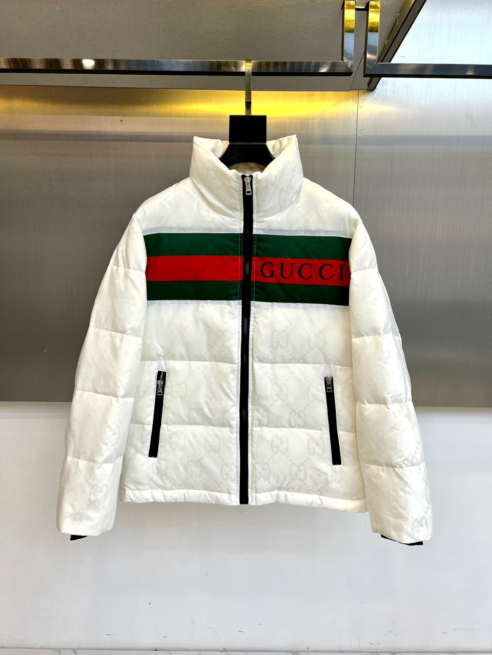 NO:656088,Gucci, the new 2025 autumn and winter down jacket, has a loose silhouette and a straight high collar, which not only provides a warm package, but also outlines a neat and modern silhouette. The front of the garment is decorated with the brand's iconic red and green webbing, with a striking black 'GUCCI' printed on it.  The words instantly light up the whole thing, becoming a core detail that pays homage to classics and is highly recognizable. The black zipper and pocket trim form a sharp visual contrast with the pure white body, adding a sense of layering and sophistication. The black cuff design at the cuffs further echoes the overall color aesthetic.  The body is made of light and warm high-quality fabrics, filled with high-quality down, putting comfort first. This down jacket perfectly combines the brand's distinctive iconic elements with a simple and practical modern design, whether it is paired with casual jeans or incorporated into a more stylish skirt.  They can easily handle a variety of occasions, becoming a fashion statement with both warm grace and Italian style on the winter streets. 48-56 (model weighs 173,143 pounds, upper body size 50),,gucci,gucci,skirts,jeans,down  jacket,alexander wang19860909Gucc古驰、2025秋冬新款羽绒服,宽松廓形融合挺立高领,在提供温暖包裹的同时,亦勾勒出利落摩登的轮廓.衣身正面饰有品牌标志性的红绿织带,其上印有醒目的黑色“GUCCI”字样,瞬间点亮整体,成为致敬经典又极具辨识度的核心细节.黑色拉链与口袋镶边,与纯净白色主体形成鲜明视觉对比,增添层次与精致感.袖口处的黑色收口设计,进一步呼应整体色彩美学.整体甄选轻盈保暖的优质面料,内充高品质羽绒,将舒适体感置于首位.这款羽绒服完美融合了品牌鲜明的标识性元素与简约实穿的现代设计,无论是搭配休闲牛仔裤,或是融入更具造型感的裙装,皆能轻松驾驭多种场合,成为冬日街头兼具温暖风度与意式格调的时尚宣言.48-56（模特173,143斤上身50码）,,gucci,gucci,skirts,jeans,down jacket,alexander wang,Men's clothing
