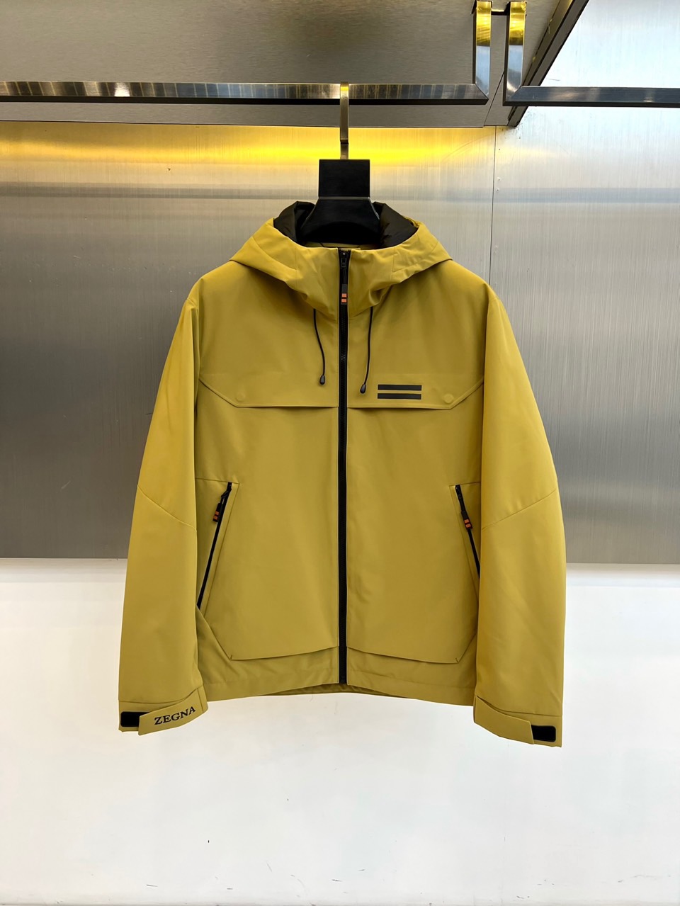 NO:656112,Zegna (goose down), the new goose down jacket for autumn and winter 2025, uses warm and bright yellow tones to interpret the fusion of urban vitality and luxurious functions. The style adopts a hooded design, with a smooth black zipper opening and closing, and the brim can be adjusted to enhance wind protection.  There are two symmetrical zippered pockets on the chest, and three black lines are decorated above the pockets to enrich the visual hierarchy. The left cuff is decorated with the 'ZEGNA' brand logo. The inside is made of black fabric, which contrasts sharply with the bright yellow outer layer, highlighting the ingenious details.  The fabric and lining are both made of polyester fiber, which is lightweight and windproof. The filling is 90% goose down and 10% feather, which provides reliable warmth with a light body feel. The quilting process is even and meticulous, ensuring that the down filling is full and not easy to shift. The filling in the sleeve cap is also polyester fiber to ensure local styling and comfort.  Combining Italian exquisite craftsmanship with outdoor practical aesthetics, the three-stripe decoration and contrasting lining become a low-key fashion statement. This goose down jacket can not only cope with urban autumn and winter commuting, but its bright color and neat tailoring can also inject vitality into outdoor casual styles, perfectly interpreting Zegna's design philosophy of integrating high-performance materials and Italian elegance. 48-56 (model 173,143 pounds, upper body size 50),,zegna,down jacket,hats,alexander wang19860909Zegna杰尼亚（鹅绒）、2025秋冬新品鹅绒服,以温暖明亮的黄色调诠释都市活力与奢华机能的融合.款式采用连帽设计,搭配顺滑黑色拉链开合,帽檐可调节以增强防风防护性.胸前设有两个对称的带拉链口袋,口袋上方装饰三条黑色线条,丰富视觉层次.左袖口饰有“ZEGNA”品牌标识.内里采用黑色面料,与外层明快的黄色形成鲜明对比,彰显细节巧思. 面料与里料均采用聚酯纤维,质地轻盈且具备防风性能.填充物为90鹅绒与10羽毛,在轻盈体感中提供可靠的保暖性.绗缝工艺均匀细致,确保羽绒填充饱满且不易移位.袖帽里填充物亦为聚酯纤维,保障局部造型与舒适度. 将意式精湛工艺与户外实用美学相融合,三条纹装饰与对比内里成为低调的时尚宣言.这款鹅绒服既能应对都市秋冬通勤,其亮眼配色与利落剪裁亦能为户外休闲造型注入活力,完美诠释杰尼亚融合高性能材质与意式优雅的设计哲学.48-56（模特173,143斤上身50码）,,zegna,down jacket,hats,alexander wang,Men's clothing