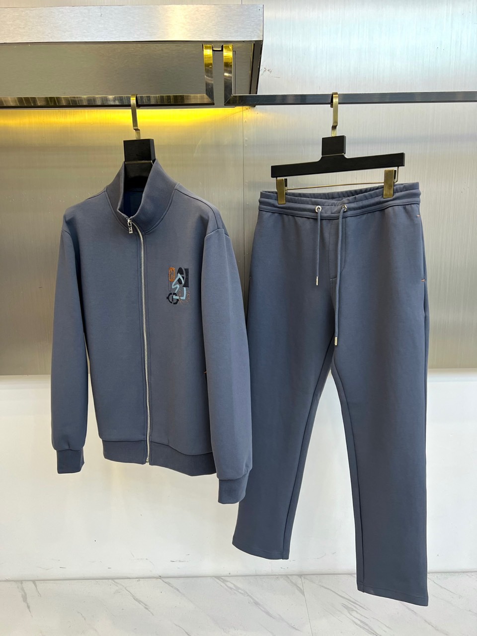 NO:726337,after the year  H Hermès' new casual suit for autumn and winter interprets the ultimate simple modern aesthetics in elegant gray tones. The suit includes a stand-up collar zipper top and loose trousers, which are made of top-quality cotton blended fabrics to create a light and soft skin-friendly touch. The classic 'H' logo on the left chest of the top is exquisitely embellished with colorful details, and the stand-up collar design and smooth silver zipper outline a neat silhouette; the trousers are equipped with a humanized drawstring elastic waist, taking into account comfort and convenience.  sex. The whole set of clothing creates a relaxed and relaxed body line through precise three-dimensional tailoring. The exquisite stitching technology and just the right degree of looseness complement each other. The brand perfectly integrates pragmatism and luxury genes. Whether it is relaxing at home or going out to meet friends, it can show its extraordinary taste in a low-key manner, giving the wearer a calm and relaxed attitude. 48-56 (model is 173, 143 pounds, upper body size 50),, hermes,19860909年后 H爱马仕、秋冬新品休闲套装,以优雅的灰色调诠释极致简约的现代美学.套装包含立领拉链上衣与宽松束脚长裤,采用顶级棉质混纺面料打造出轻盈柔软的亲肤触感.上衣左胸处的经典“H”标识以彩色细节精致点缀,立领设计与顺滑的银色拉链勾勒出利落轮廓；裤装搭载人性化抽绳松紧腰头,兼顾舒适度与便捷性.整套服装通过精准的立体剪裁营造出松弛有度的身形线条,精湛的缝线工艺与恰到好处的宽松度相得益彰.品牌将实用主义与奢华基因完美融合,无论是居家休憩还是外出会友,都能在低调中展现不凡品味,赋予穿着者举重若轻的从容气度.48-56（模特173,143斤上身50码）,,hermes,,Men's clothing