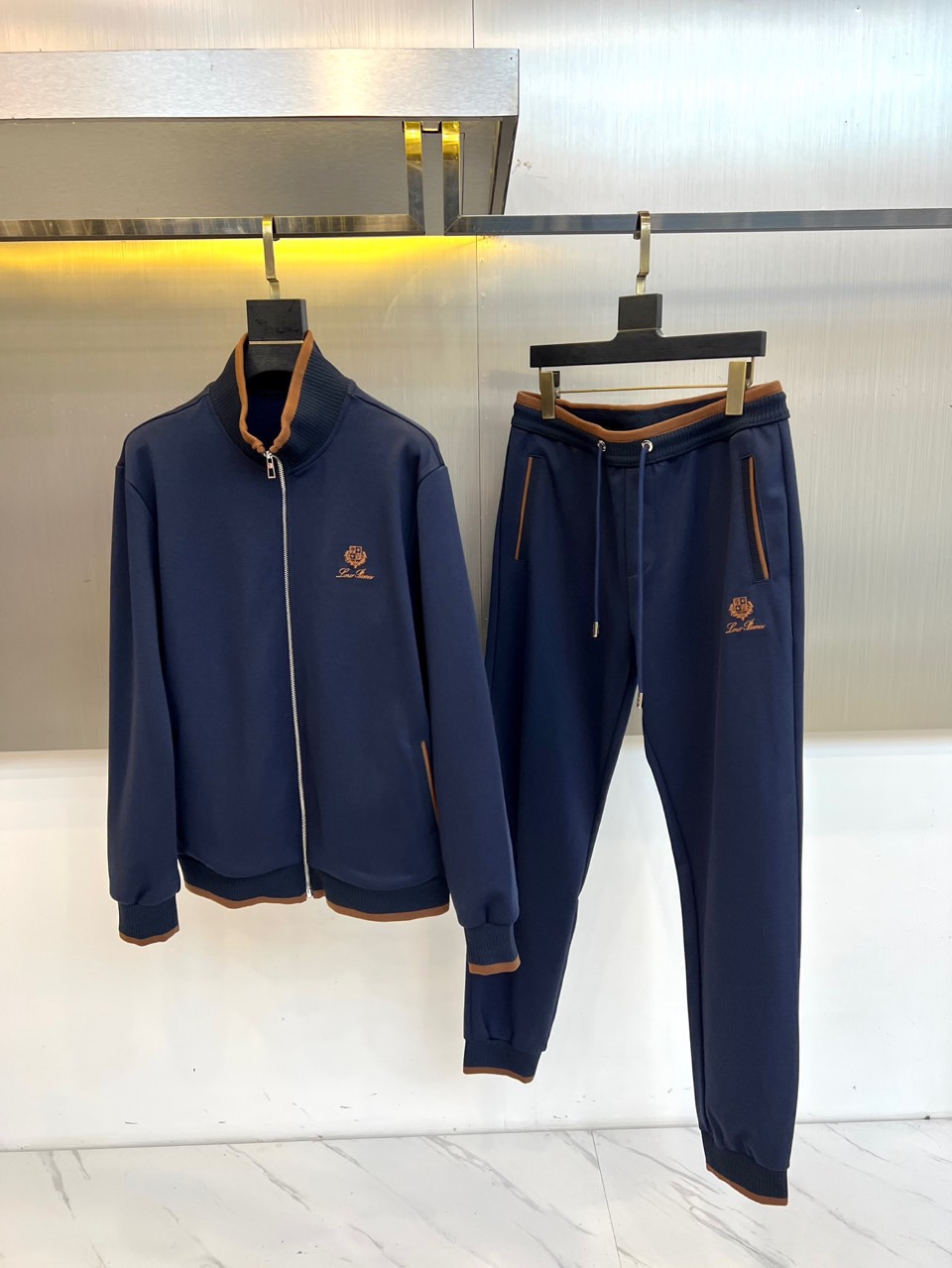 NO:726344,Loro Piana's autumn and winter sports suit after the new year, including a stand-collar zipper jacket and straight trousers, adopts simple and smooth tailoring. The essence of its design lies in the brown trim cleverly integrated into the collar, cuffs and trousers sides, which forms a high-end contrast with the main color and instantly enhances the visual level and sophistication. The brand embroidery logo on the left chest and trousers body low-key confirms the extraordinary identity.  The overall selection of soft and comfortable high-performance fabrics ensures the freedom of movement and the dignity of daily wear. Its style perfectly balances sports functionality and casual elegance. The injection of brown details breaks the monotony of the suit and gives it a unique fashion recognition. Whether it is used for light exercise or as high-quality casual wear for daily travel, it can be controlled calmly, showing effortless high-end taste between movement and stillness. M-4XL (model 173, 143 pounds, upper body size L), loro piana, jackets &  coats,19860909年后 Loro Piana 秋冬运动套装,款式包含立领拉链夹克与直筒长裤,采用简约流畅的剪裁.其设计精髓在于领口、袖口及裤侧巧妙融入的棕色饰边,与主色调形成高级对比,瞬间提升视觉层次与精致度.左胸与裤身的品牌刺绣徽标,低调印证非凡身份. 整体选用柔软舒适的高性能面料,确保运动时的自由与日常穿着的体面.其风格完美平衡了运动功能性与休闲优雅感,棕色细节的注入打破了套装的单调,赋予其独特的时尚辨识度.无论是用于轻度运动,或作为日常出行的高品质休闲着装,皆能从容驾驭,于动静之间展露毫不费力的高级品味.M-4XL（模特173,143斤上身L码）,,loro piana,jackets & coats,,Men's clothing