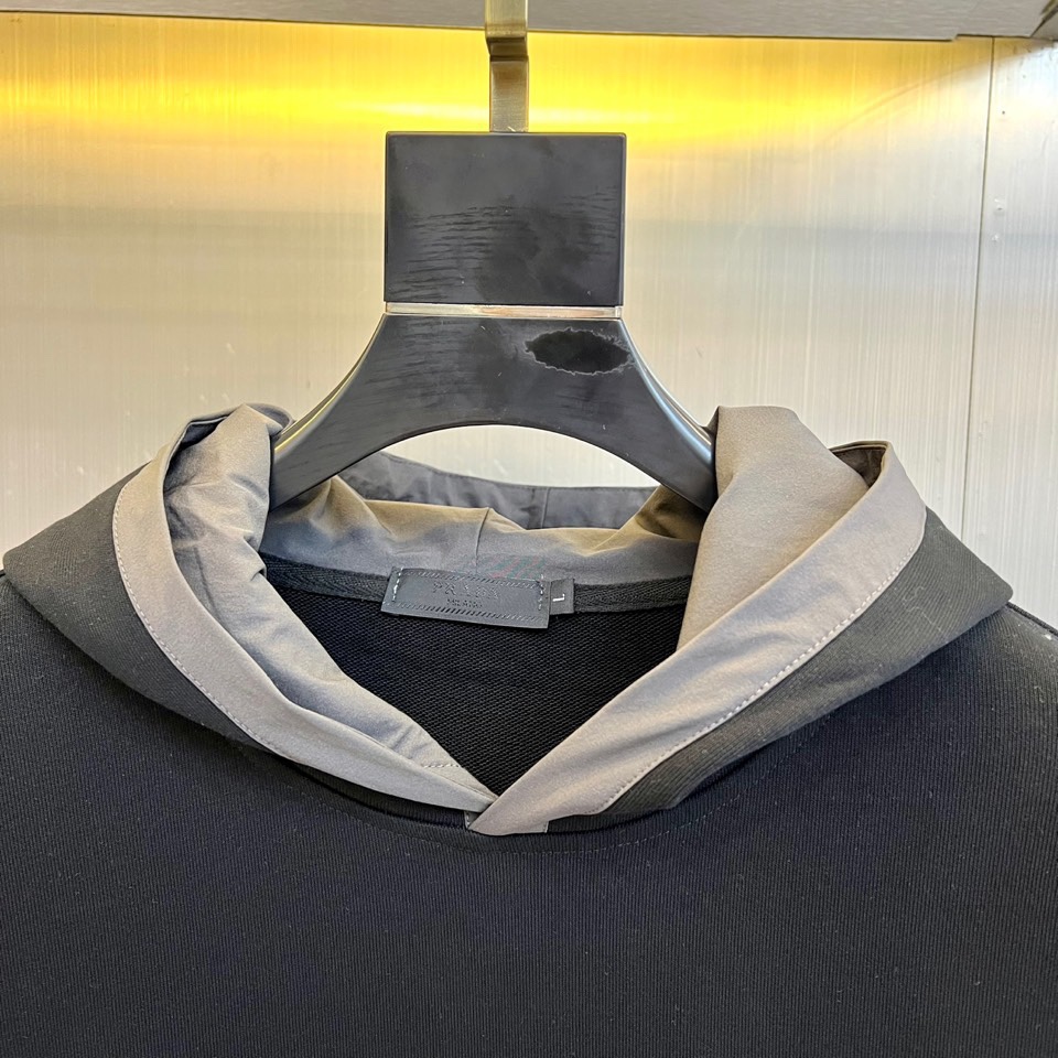 Prad普拉、2025秋冬新作连帽卫衣，款式采用连帽设计搭配可调节抽绳，胸前饰有品牌标志性三角徽标，下方