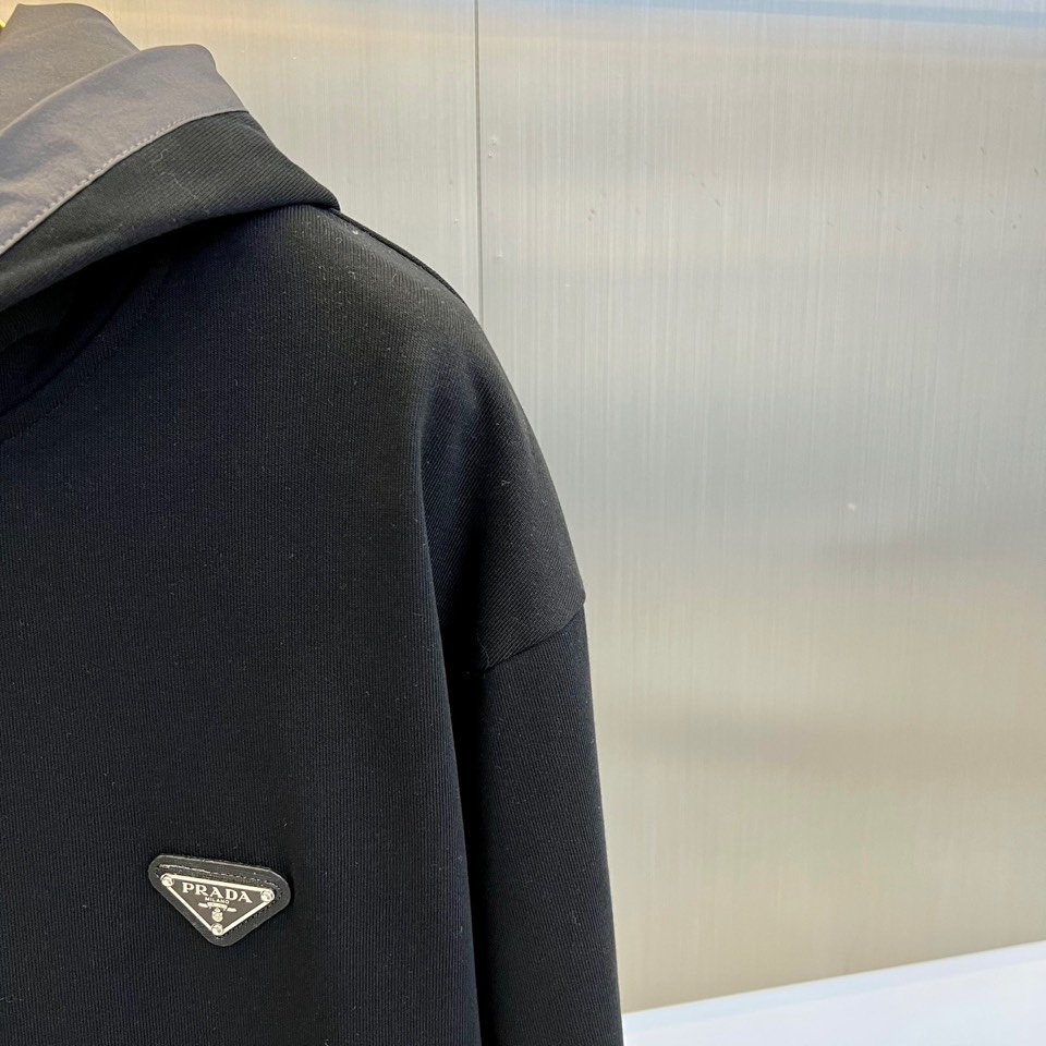 Prad普拉、2025秋冬新作连帽卫衣，款式采用连帽设计搭配可调节抽绳，胸前饰有品牌标志性三角徽标，下方