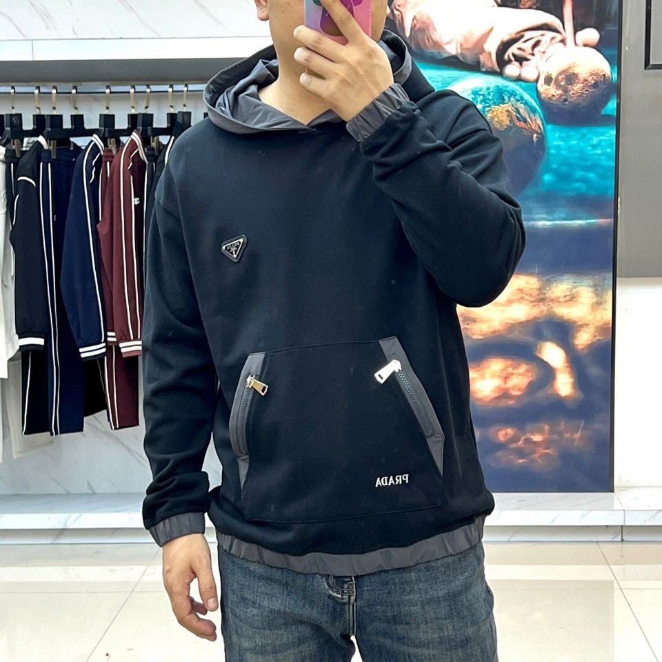 Prad普拉、2025秋冬新作连帽卫衣，款式采用连帽设计搭配可调节抽绳，胸前饰有品牌标志性三角徽标，下方