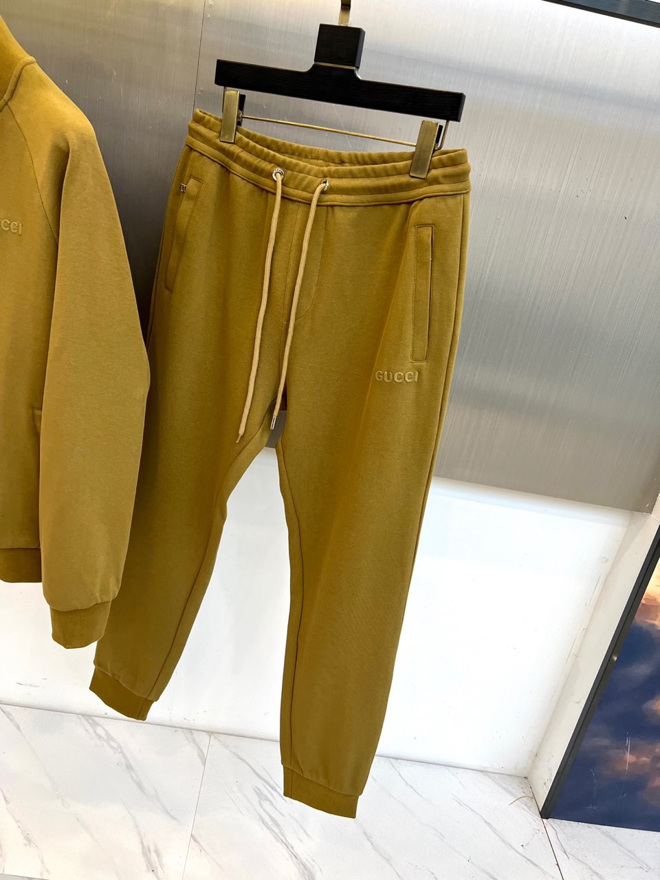 Gucc古驰、2025秋冬新品 GU暖棕休闲套装。这款暖棕色套装由立领拉链外套与抽绳束脚裤组成整体造型。