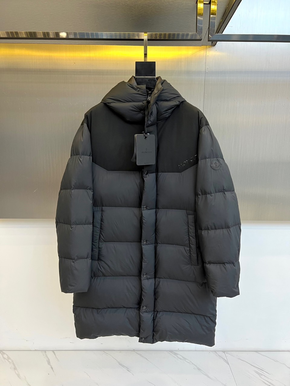 Mon蒙口（纯鹅绒）、2025秋冬新品长款羽绒服，以经典黑色演绎冬日奢华防护美学。这款羽绒服采用100%