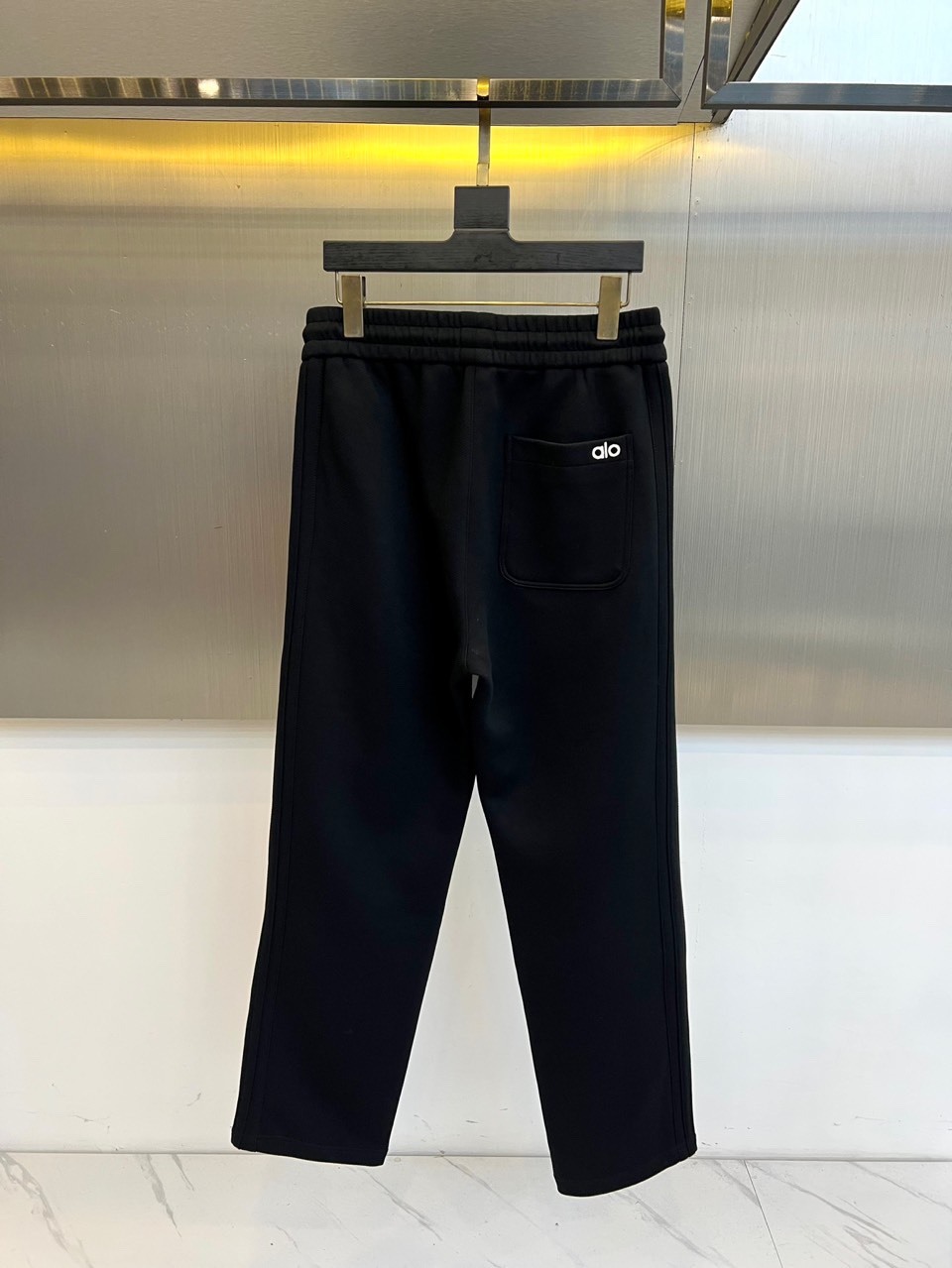Alo-2025秋冬新品运动裤，款式采用直筒廓形搭配弹性抽绳腰头，裤身两侧饰有线条装饰延伸至裤脚，左腿处