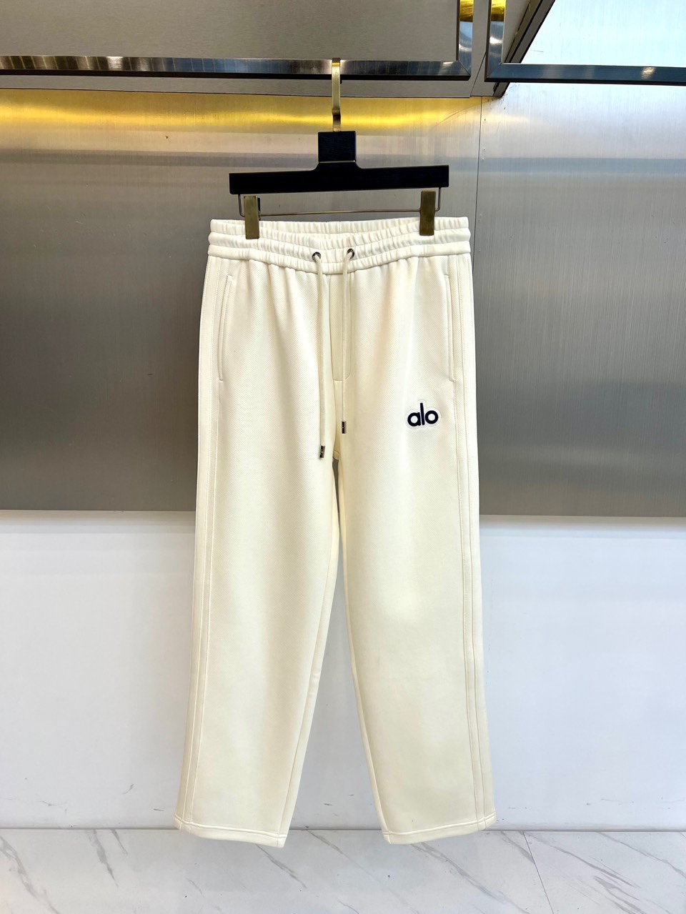 Alo-2025秋冬新品运动裤，款式采用直筒廓形搭配弹性抽绳腰头，裤身两侧饰有线条装饰延伸至裤脚，左腿处