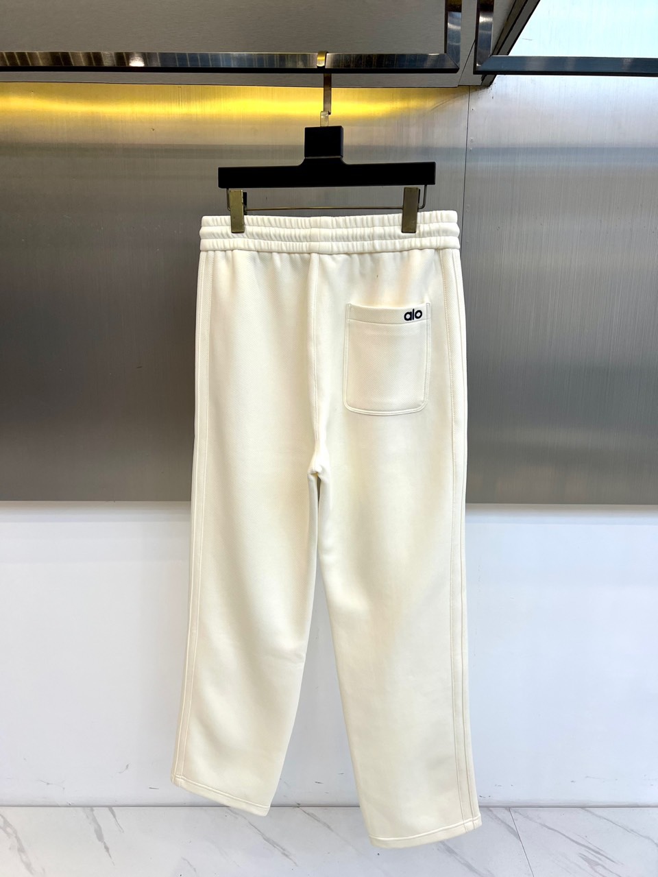 Alo-2025秋冬新品运动裤，款式采用直筒廓形搭配弹性抽绳腰头，裤身两侧饰有线条装饰延伸至裤脚，左腿处