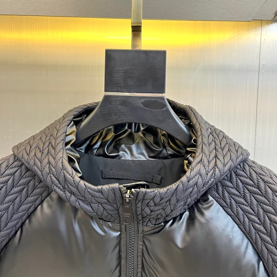 Prad普拉达、2025秋冬新款男士羽绒服，这款连帽羽绒服采用横向绗缝工艺勾勒出饱满的立体轮廓，衣袖部位