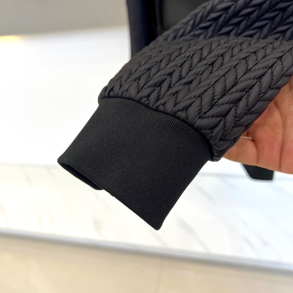 Prad普拉达、2025秋冬新款男士羽绒服，这款连帽羽绒服采用横向绗缝工艺勾勒出饱满的立体轮廓，衣袖部位