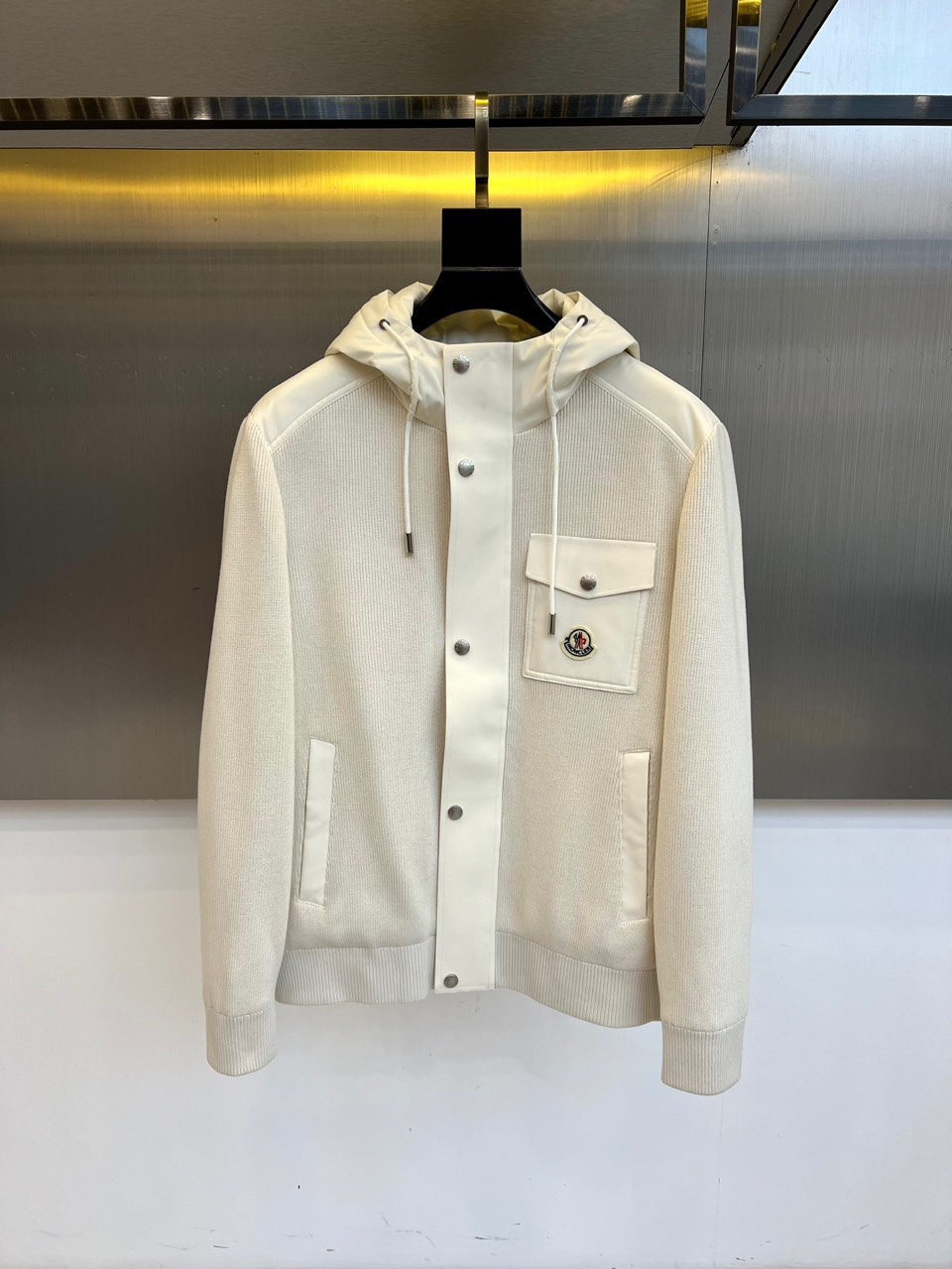 Mon蒙口、2025秋冬新品都市针织拼接羽绒服外套夹克。连帽设计搭配银色纽扣开合系统，左胸贴袋饰有品牌经