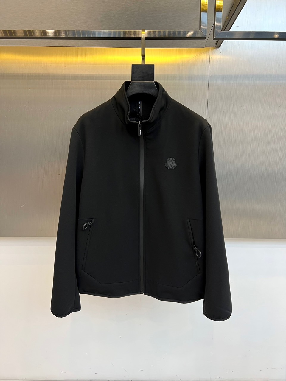 Mon蒙口、2025秋冬新品男士夹克，以简约轮廓重塑日常优雅。本品采用经典黑色面料，立领设计赋予颈部利落