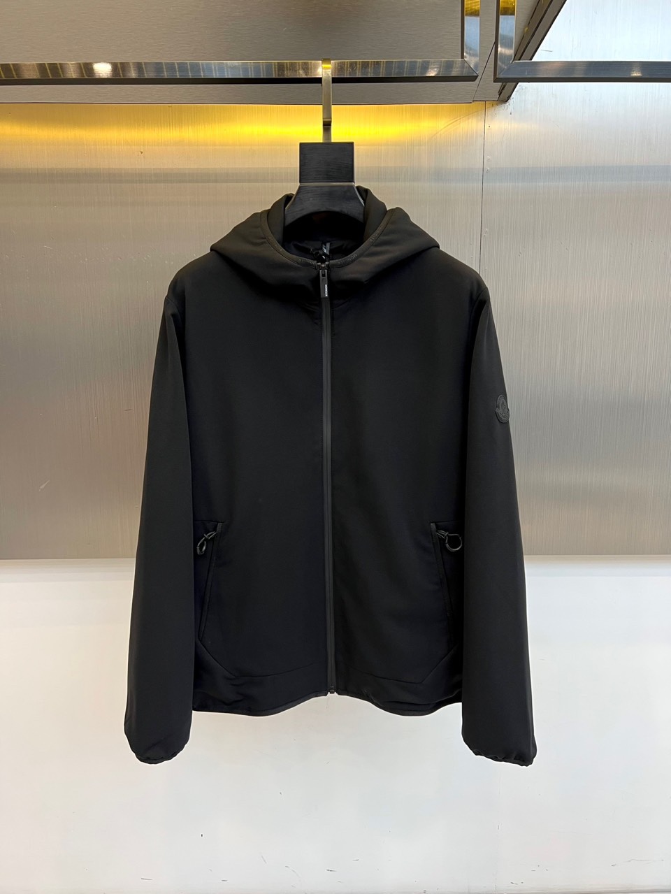 Mon蒙口、2025秋冬新款男士连帽外套，以极简设计诠释现代日常美学。本品采用质感出色的黑色面料，剪裁利