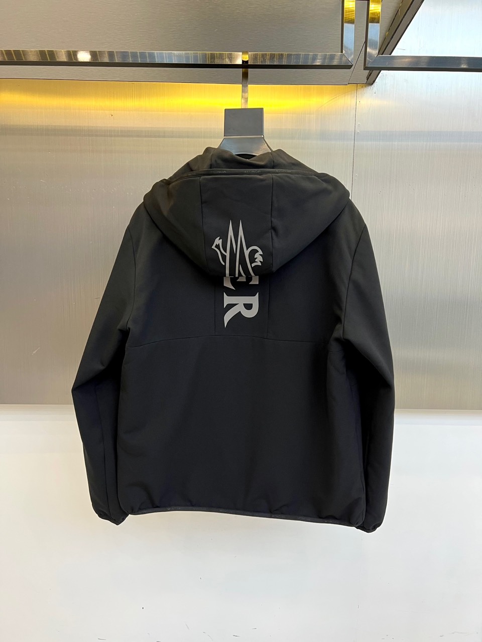 Mon蒙口、2025秋冬新款男士连帽外套，以极简设计诠释现代日常美学。本品采用质感出色的黑色面料，剪裁利