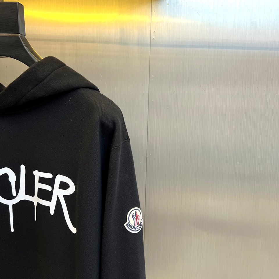 Mon蒙口、2025秋冬新品加绒连帽卫衣，款式采用经典连帽与宽松版型，胸前饰以醒目的黑色泼墨涂鸦“MON