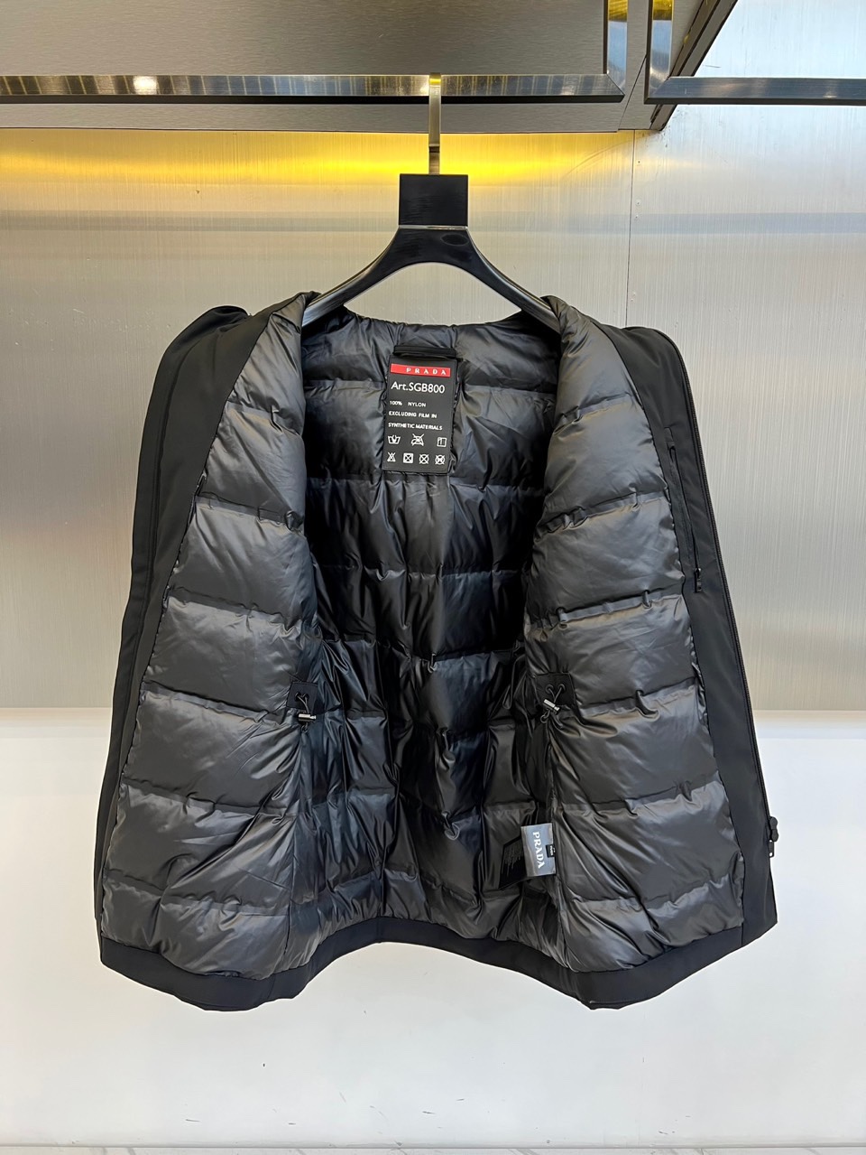 Prad普拉（鹅绒）、2025秋冬新品鹅绒中长款羽绒服，以经典黑色演绎永恒奢华。中长版型兼顾保暖与风度，