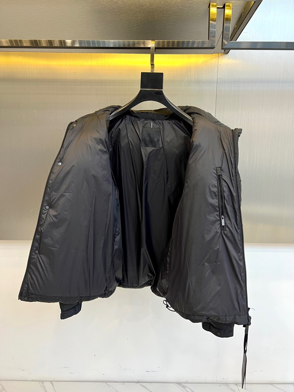 Mon蒙口（鹅绒）、2025秋冬新品黑色羽绒服，连帽设计搭配可调节防风系统，左袖饰有反光品牌徽章提升夜间