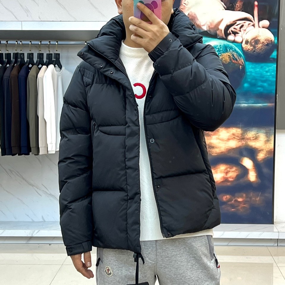 Mon蒙口（鹅绒）、2025秋冬新品黑色羽绒服，连帽设计搭配可调节防风系统，左袖饰有反光品牌徽章提升夜间